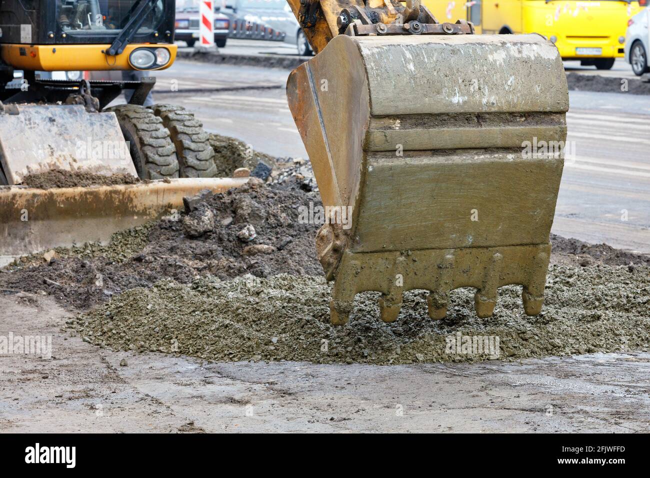 A road excavator bucket pours concrete gravel at a construction site. Close-up. Stock Photo