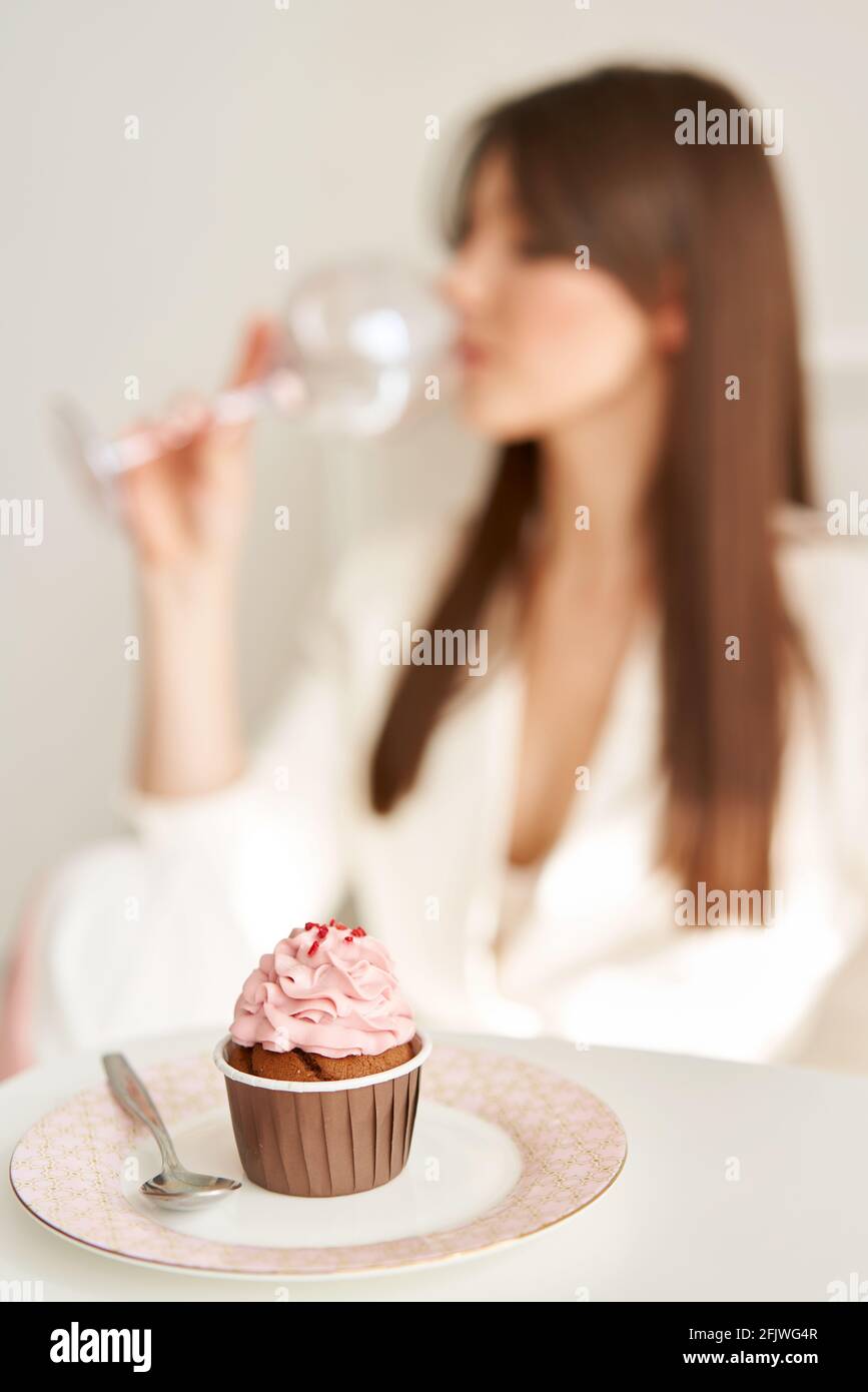 woman eating pink cupcake on the plate, by little spoon. Stock Photo
