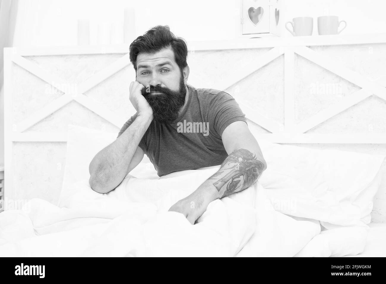 unshaven caucasian man woke up alone in bed with white linen at home, bedtime Stock Photo