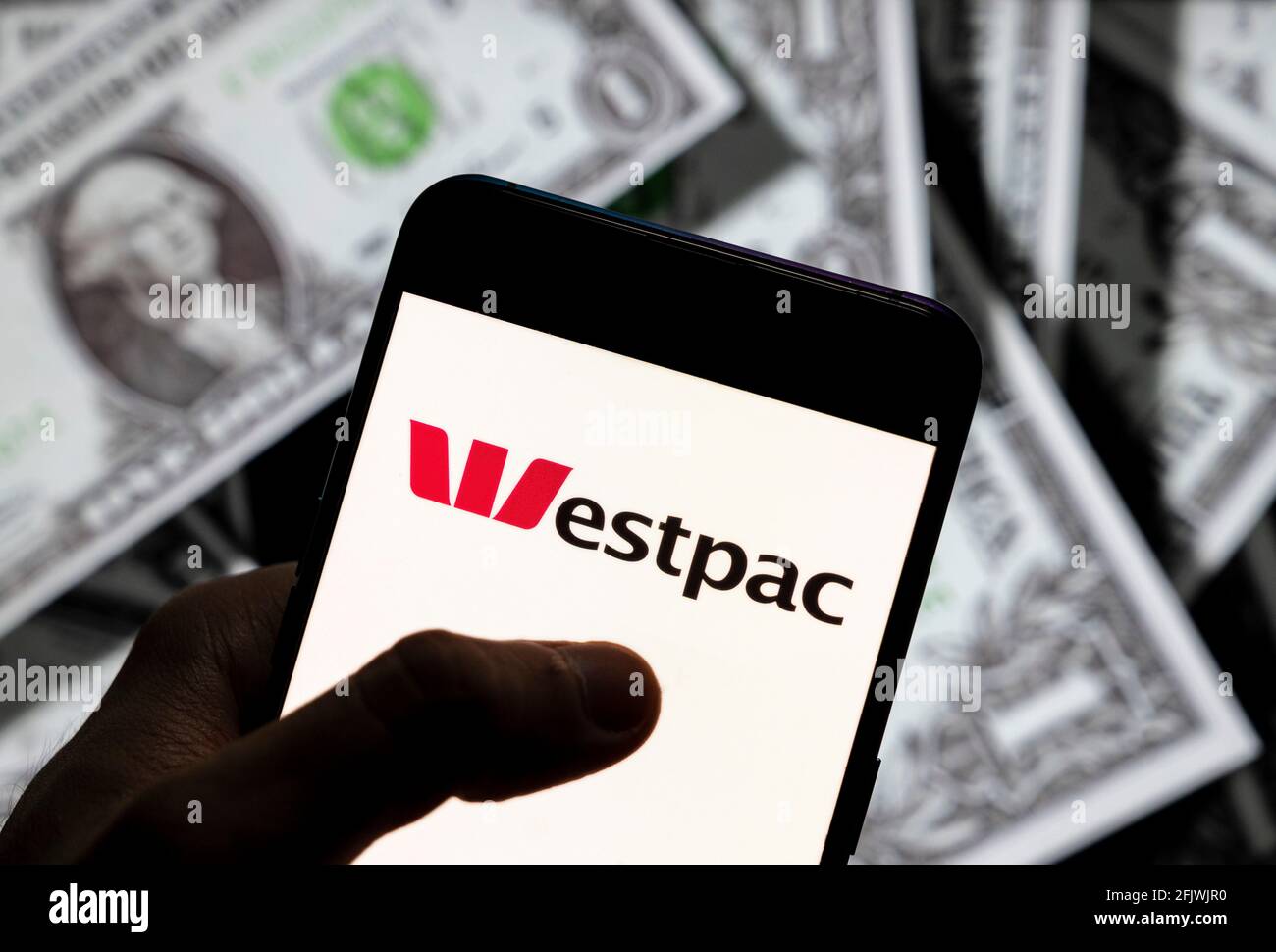 In this photo illustration the Australian bank and financial-services provider company Westpac Banking Corporation logo seen displayed on a smartphone with USD (United States dollar) currency in the background. Stock Photo