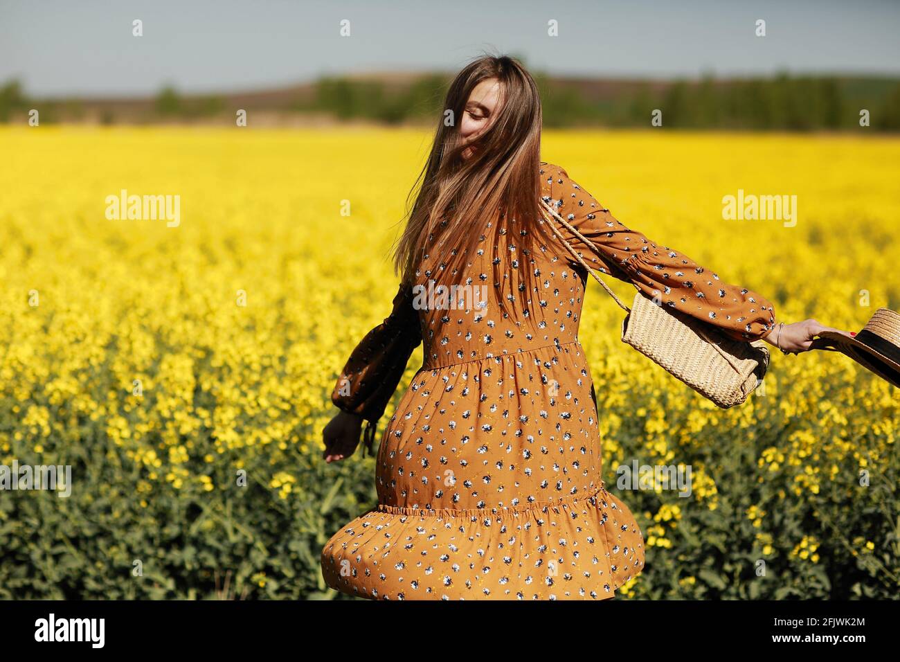 beautiful young woman walks in a field of yellow rapeseed. Girl ...
