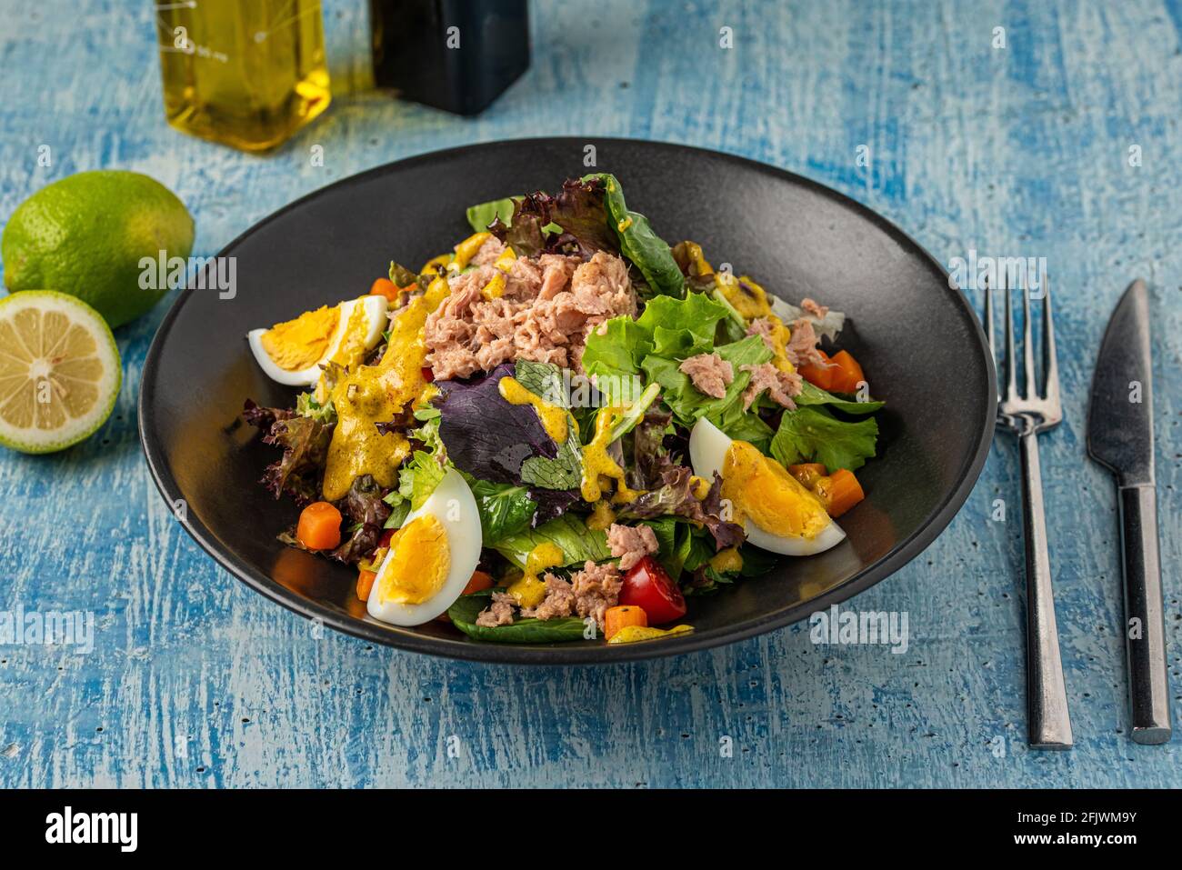 Fresh mediterranean salad with egg and tuna fish on a black plate Stock Photo