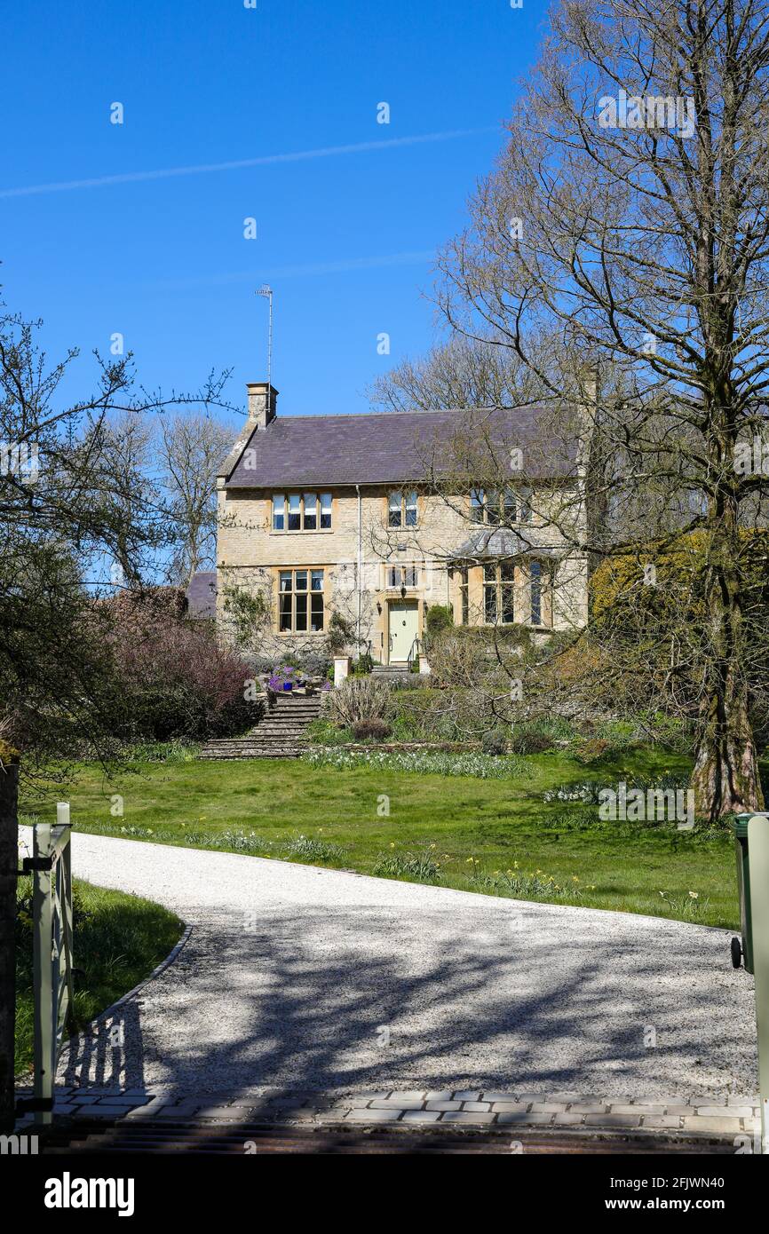 Pretty detached cottage and garden with a gated drive entrance in The Cotswolds village of Compton Abdale in Gloucestershire UK in springtime Stock Photo