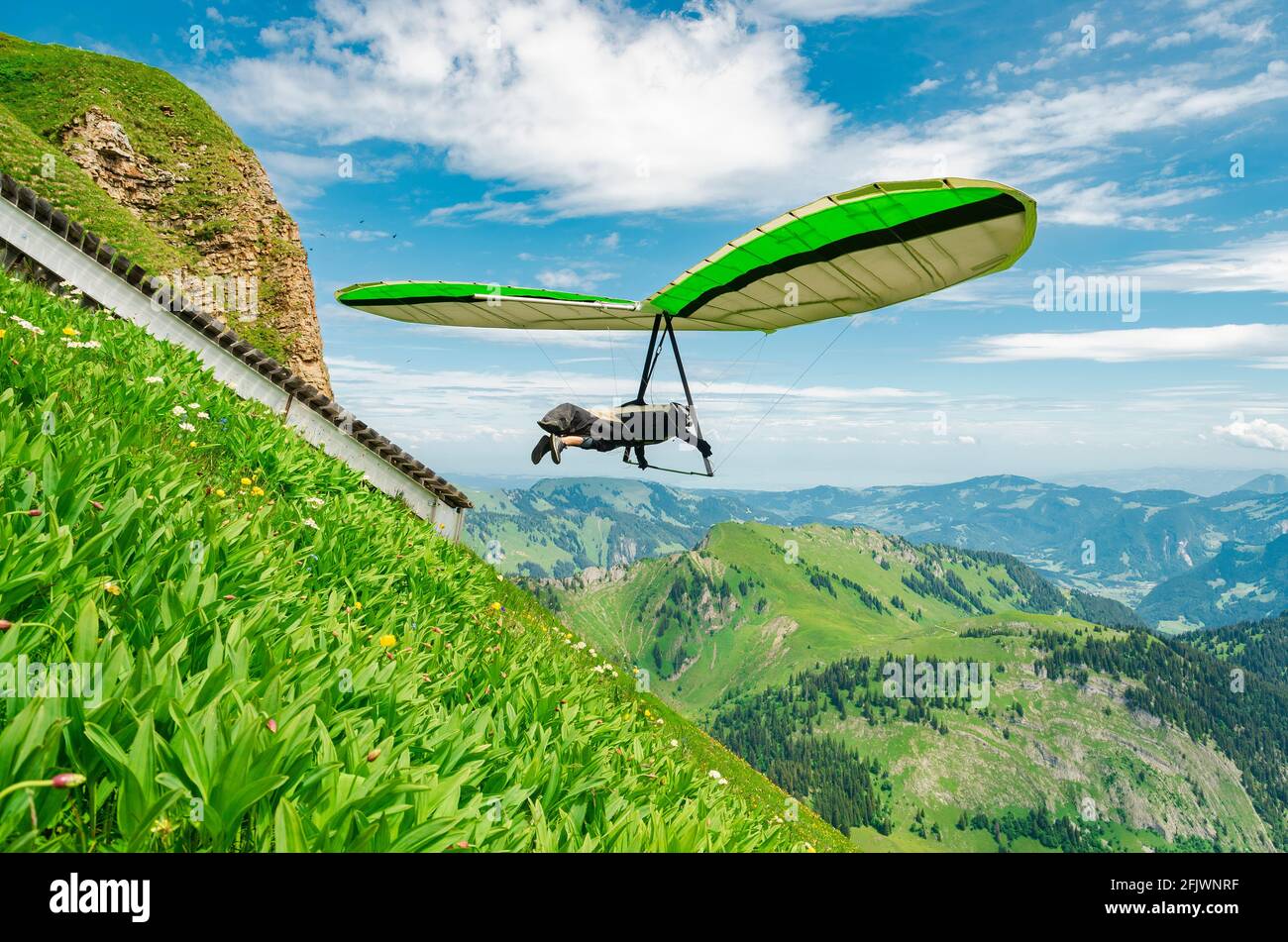 Hang glider pilots flies from steep slope high in the mountains. Diedamskopf, Austria. Extreme airborne sport. Stock Photo
