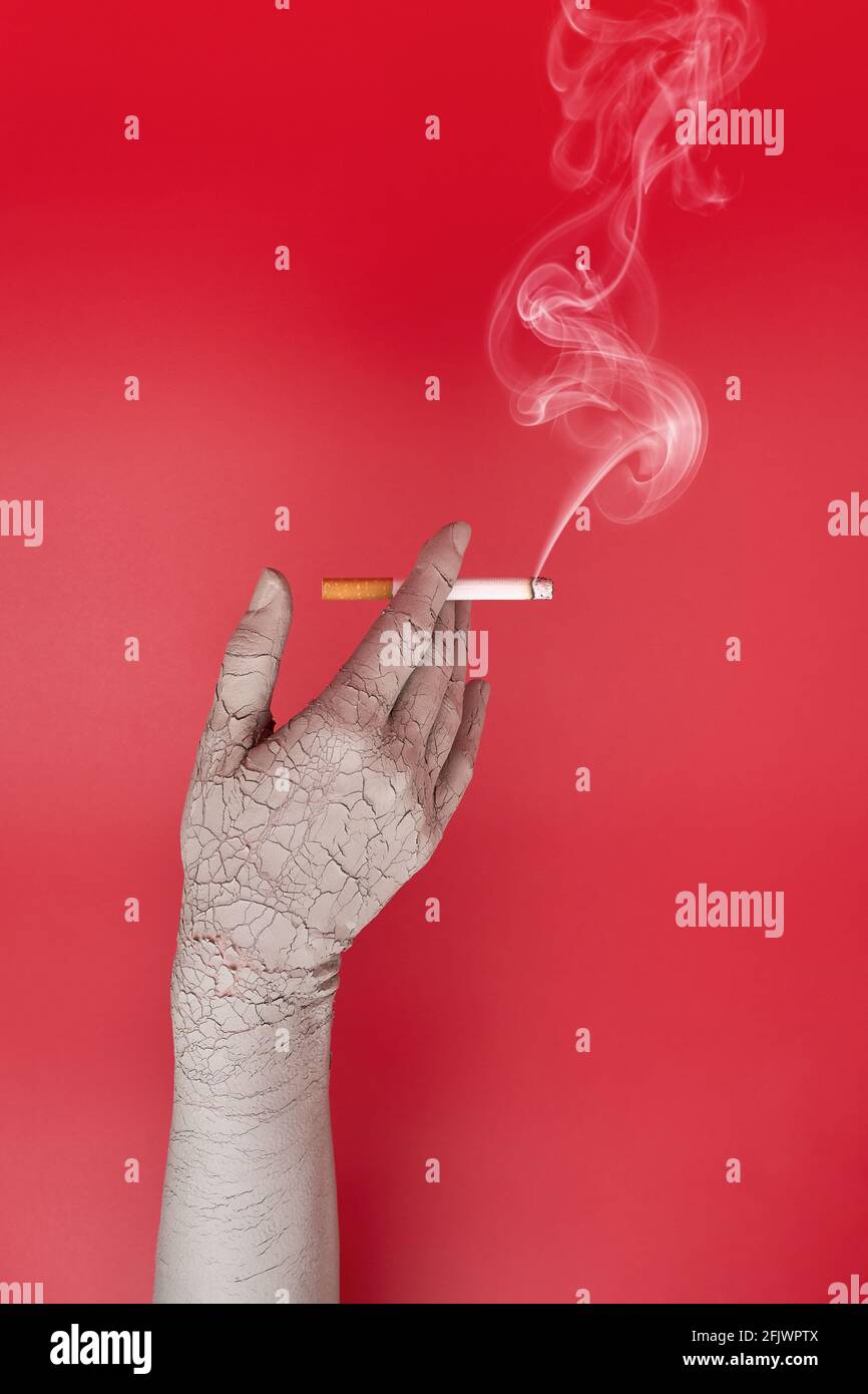 Dry and cracked hand holding a smoking cigarette. Bad effects of