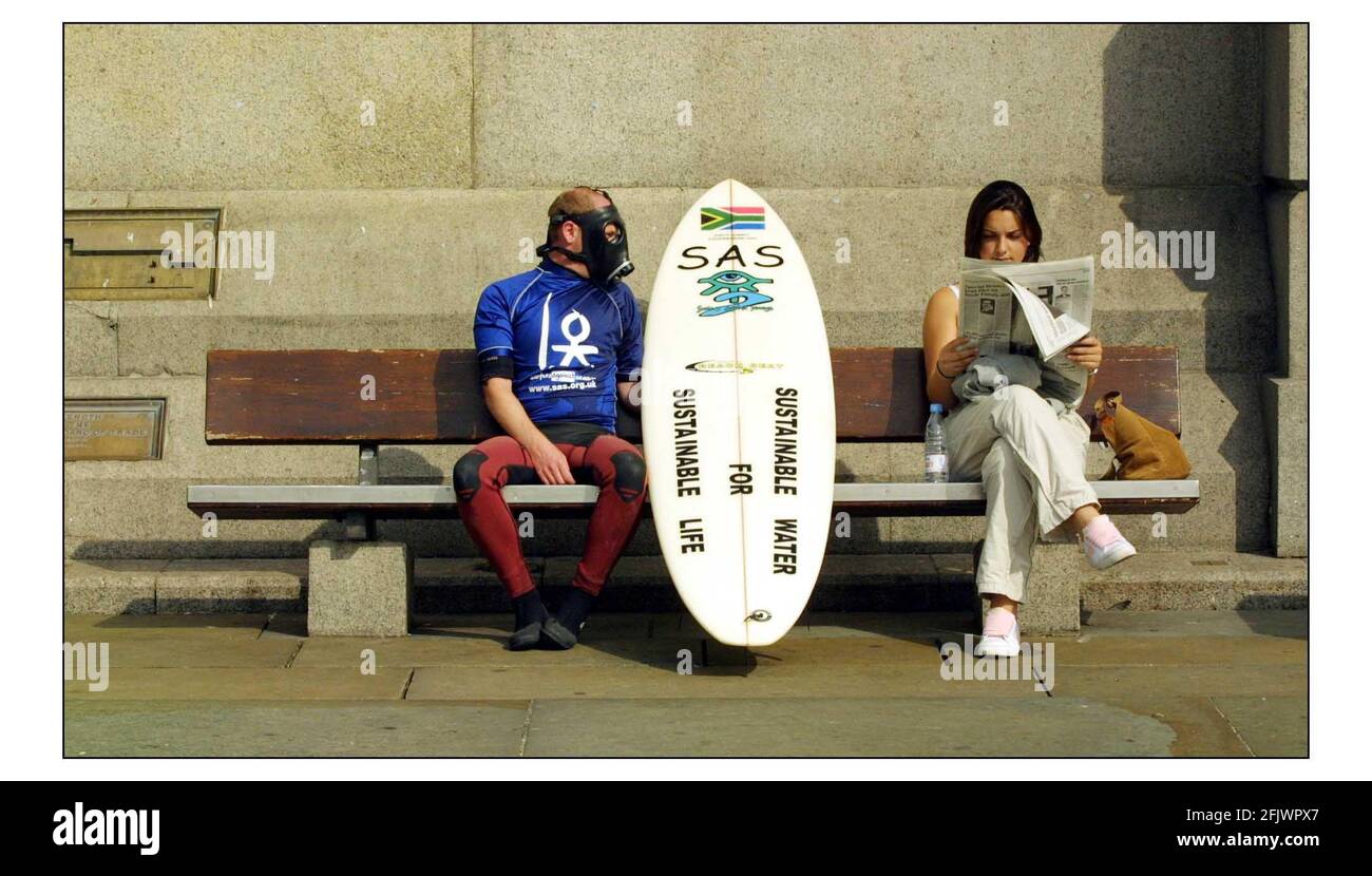 A Surfers Against Sewage Delegation of wetsuited surfers with gasmasks and messages of Sustainable Water for Sustainable Life on their surfboards in Trafalgar Square before delivering a large bag of recycled sewage sludge to the South African High Commission ahead of the Earth summit in Johannesburg next week.pic David Sandison 22/8/2002 Stock Photo