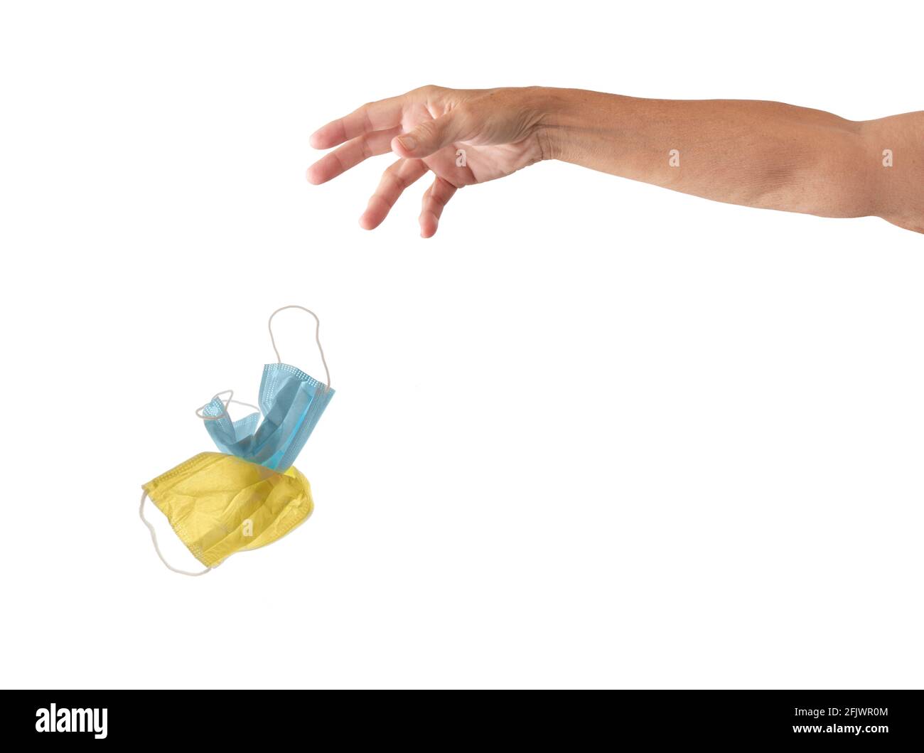 Hand and arm discarding two Covid face masks, isolated on white with copy space or to be easily extracted and placed into another image. Stock Photo