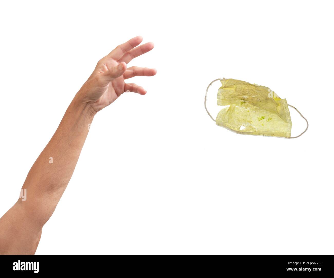 An arm throwing away a soiled yellow face mask. Stock Photo