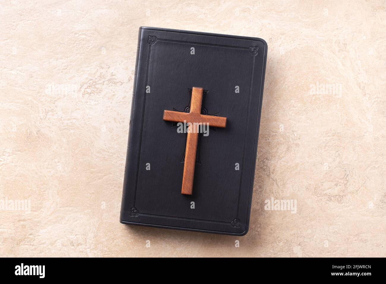 Wooden cross on Bible over marble background. Reminder of Jesus sacrifice and Christ resurrection. Easter passover. Eucharist concept. Christianity Stock Photo