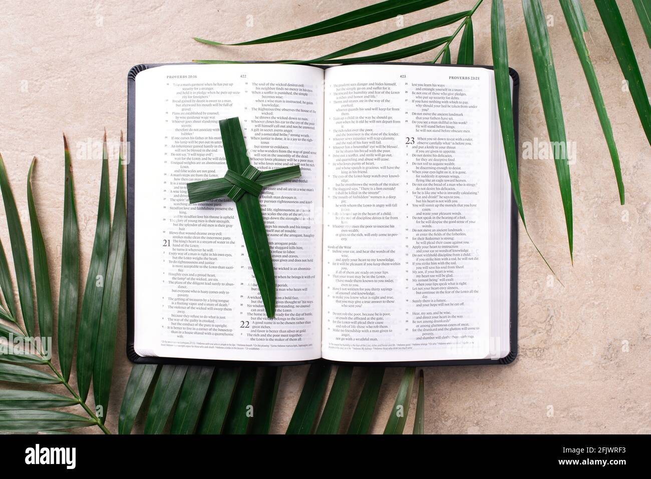 Palm Sunday concept. Palm cross on open Holy Bible and palm leaves. Reminder of Jesus sacrifice and Christ resurrection. Easter passover. Eucharist Stock Photo