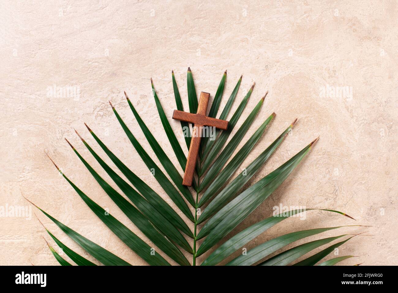 Palm Sunday concept. Wooden cross over palm leaves. Reminder of Jesus