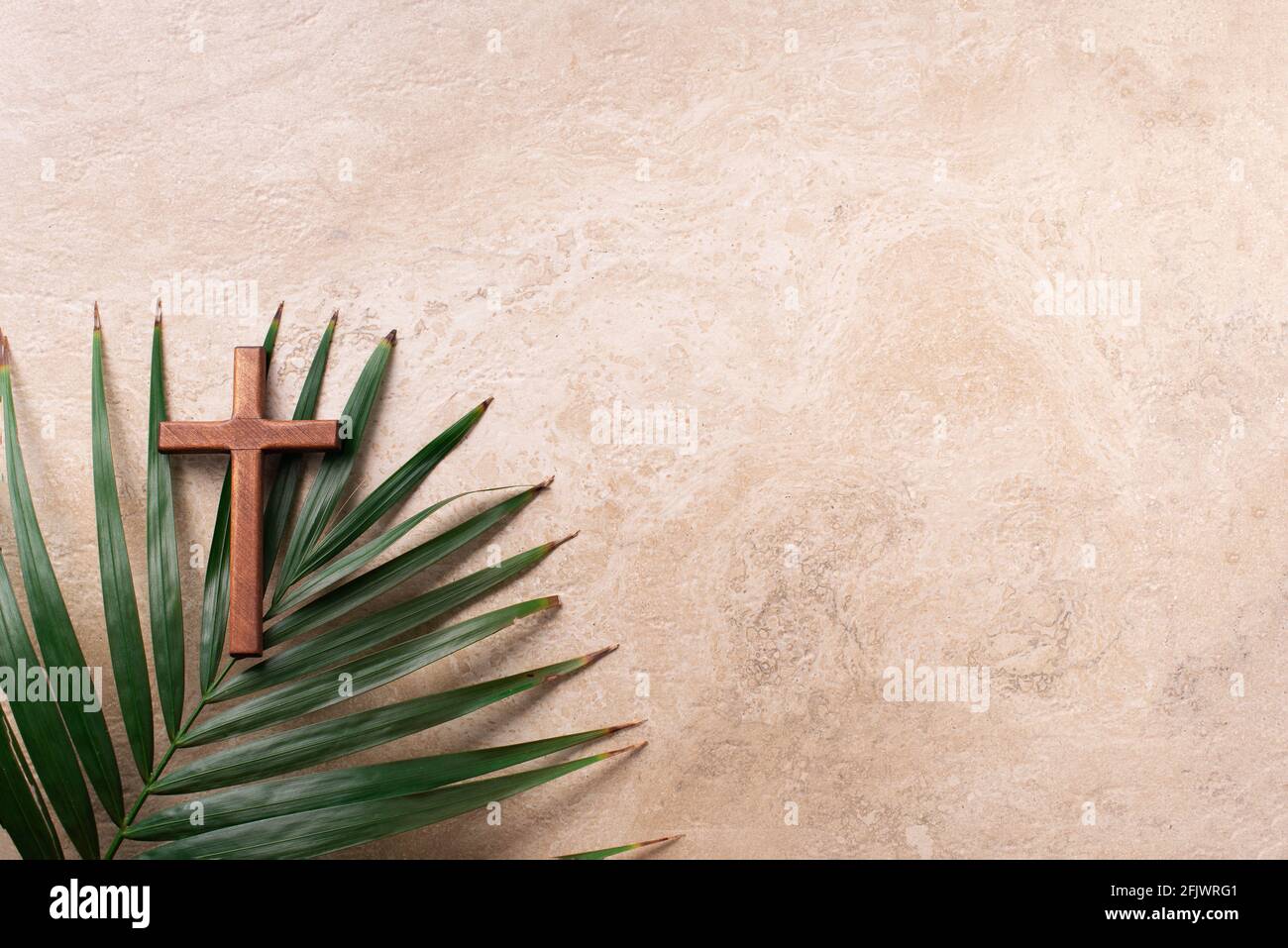 Palm Sunday concept. Wooden cross over palm leaves. Reminder of Jesus sacrifice and Christ resurrection. Easter passover. Eucharist concept Stock Photo