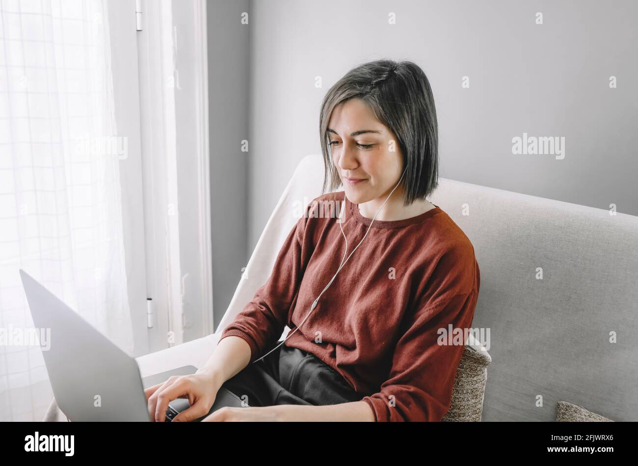 Woman working at home with her laptop and white headphones sitting on ...