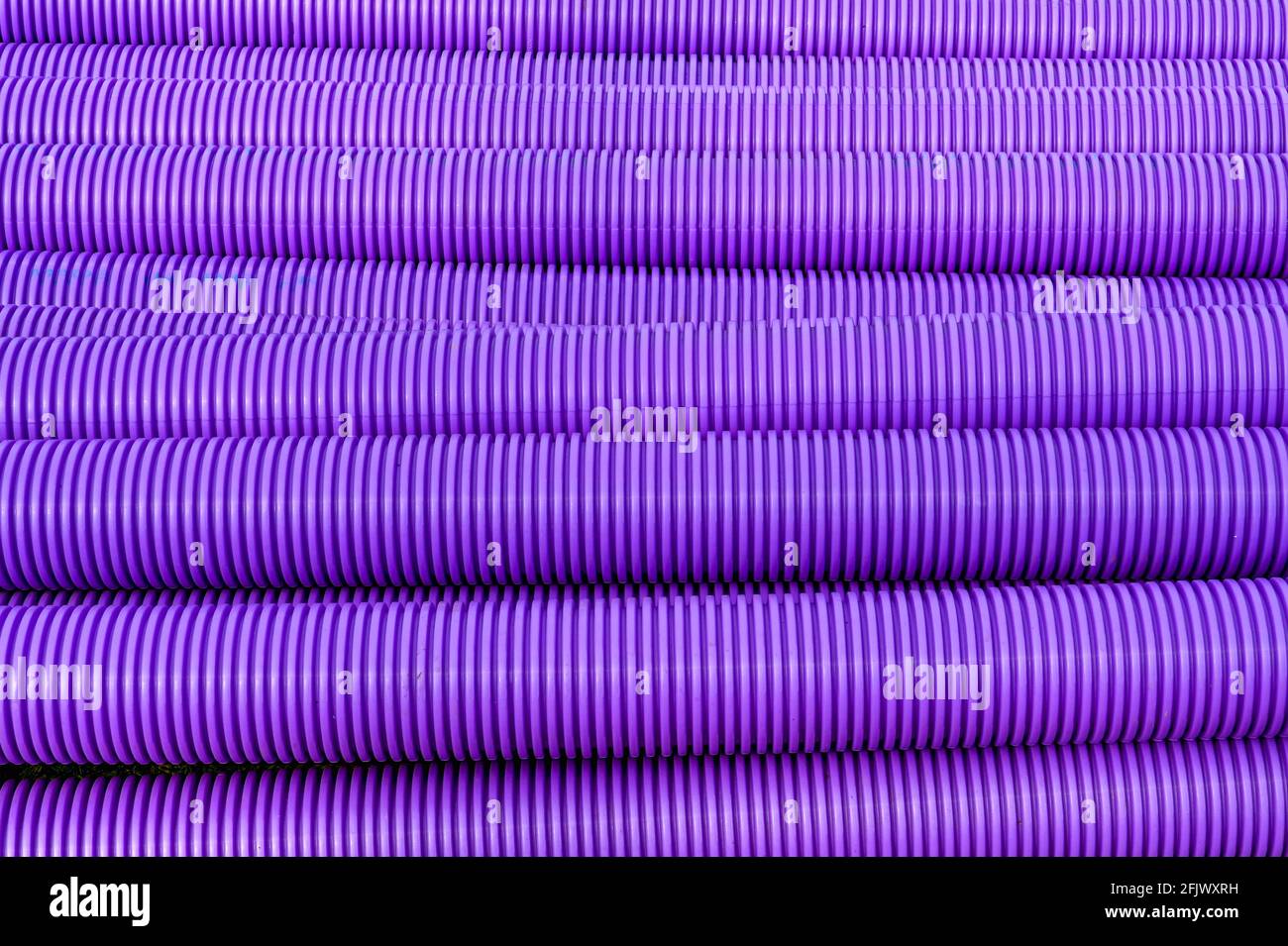 Pattern formed by purple corrugated plastic pipes used for communications cables. No people. Copy space. Stock Photo