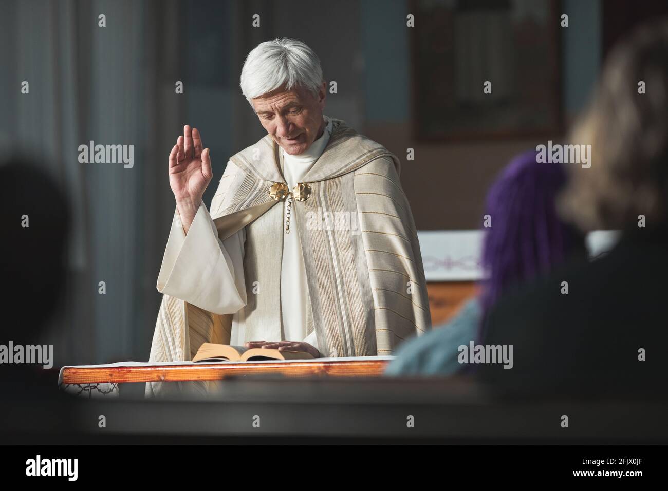 Senior priest reading the Bible for people during ceremony in the