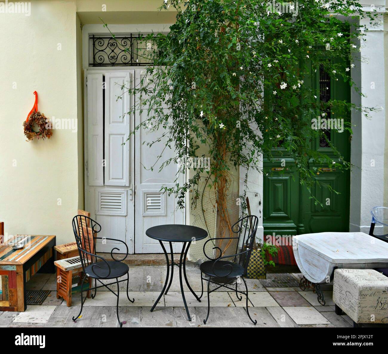 Traditional café patio with a green entrance door, a climbing jasmin