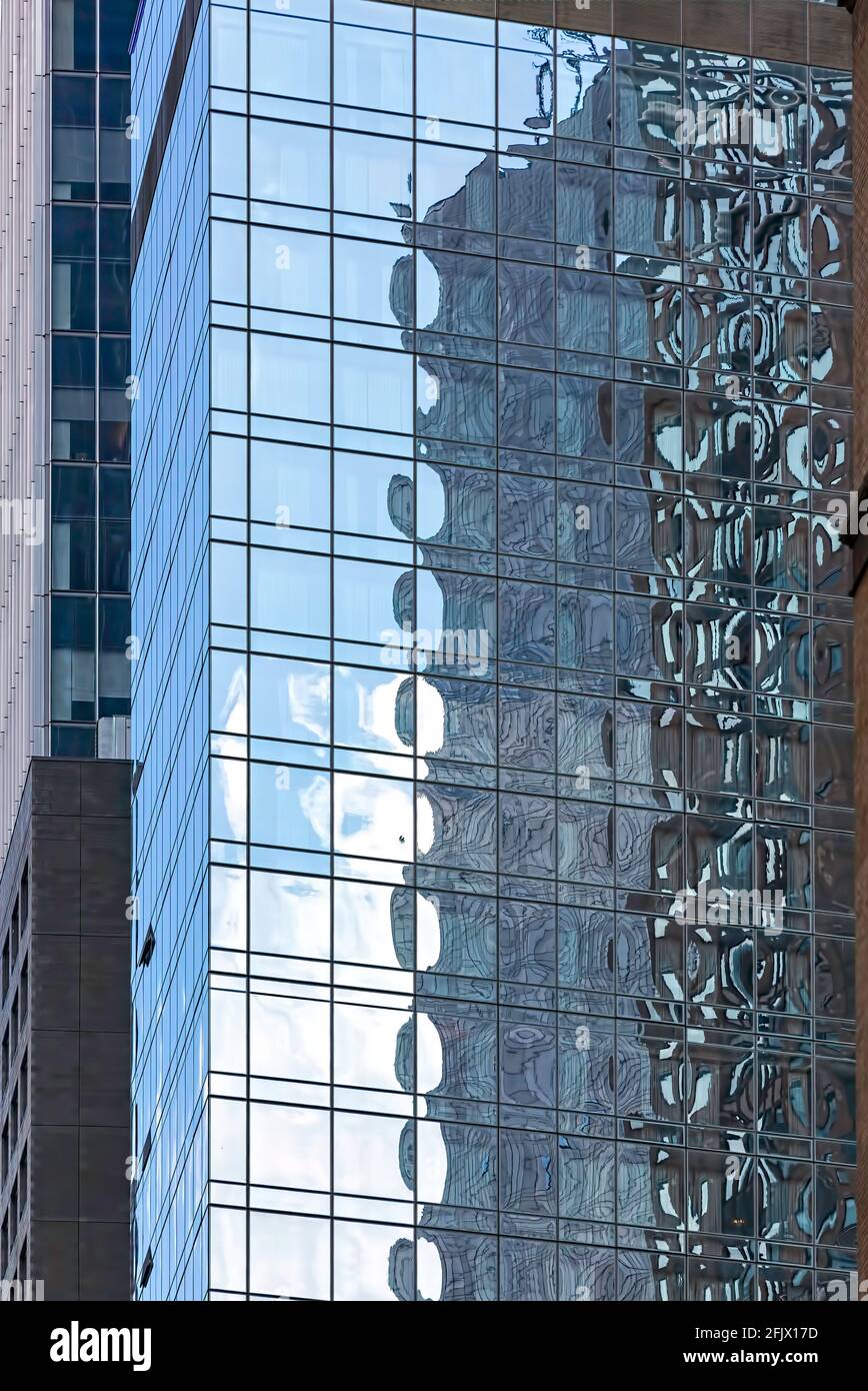 Glass facade of New York City skyscraper mirrors its surroundings. Stock Photo