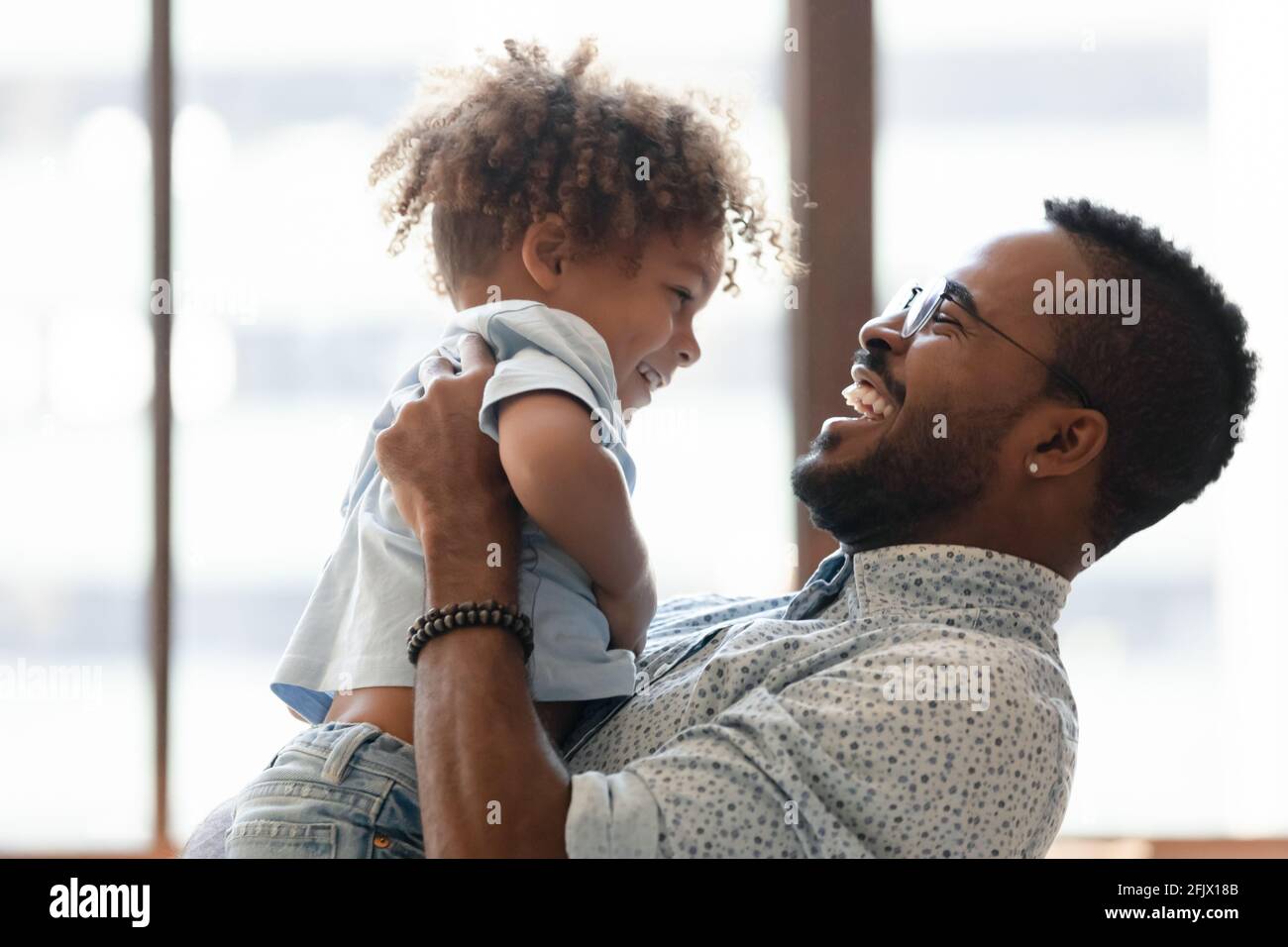 Happy daddy holding kid in arms, hugging toddler boy Stock Photo