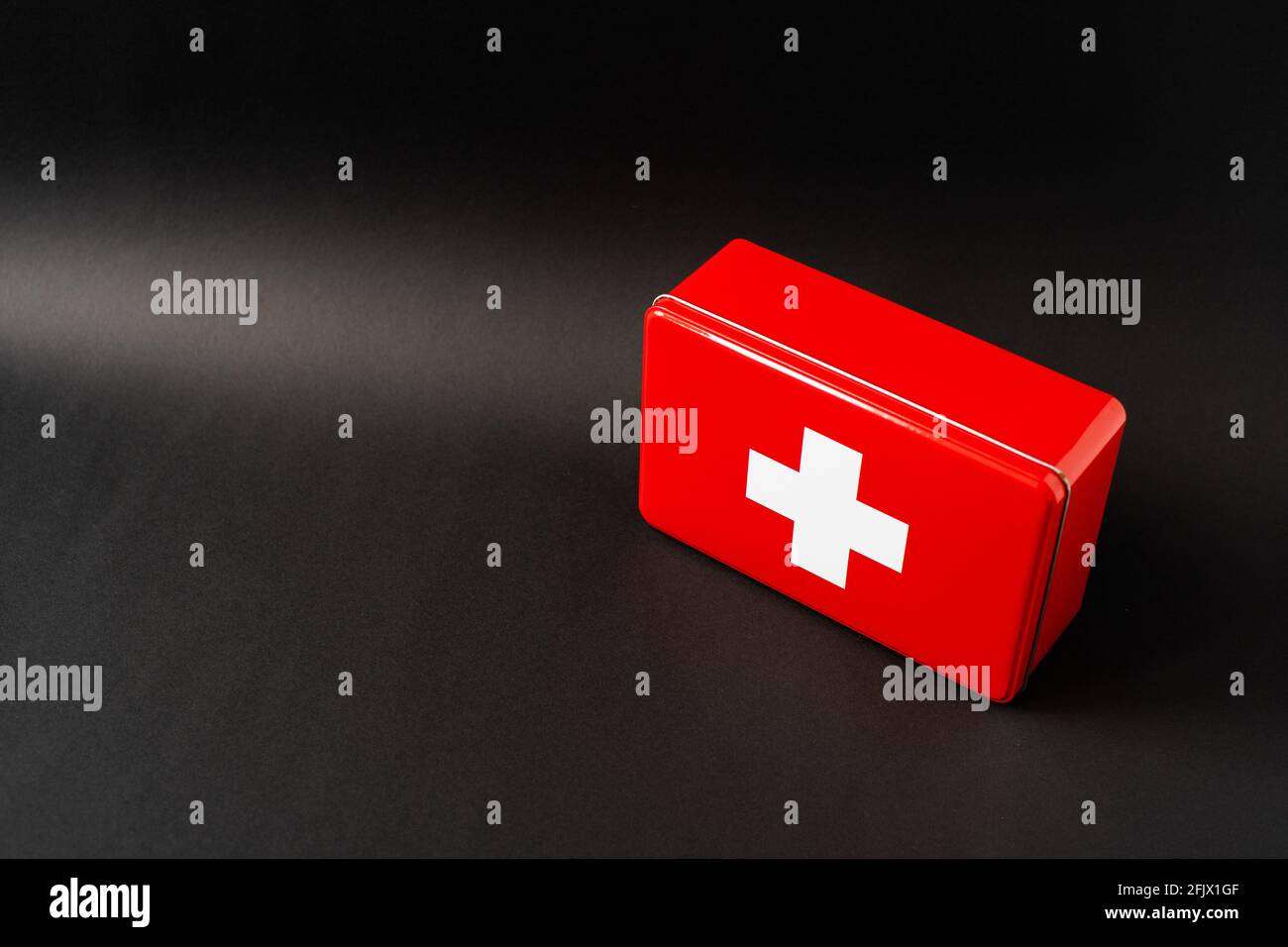 Red simplistic first aid box, black background with light gradient Stock Photo