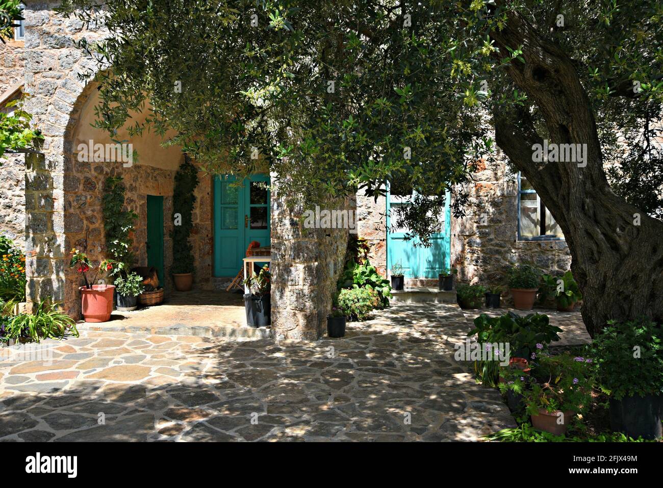 Rural stone house arched facade with a turquoise wooden door and window ...