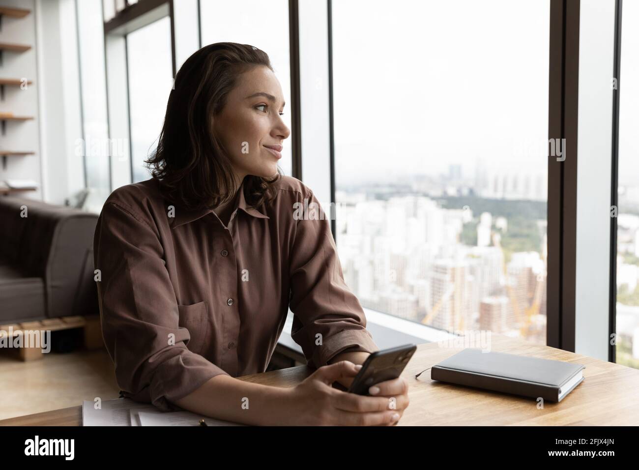 Young woman use smartphone look in distance dreaming Stock Photo
