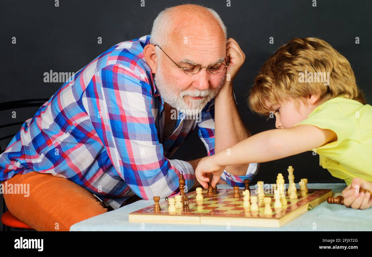 Chess competition. Grandpa and grandson playing chess spending free time together. Brain development and logic concept. Stock Photo