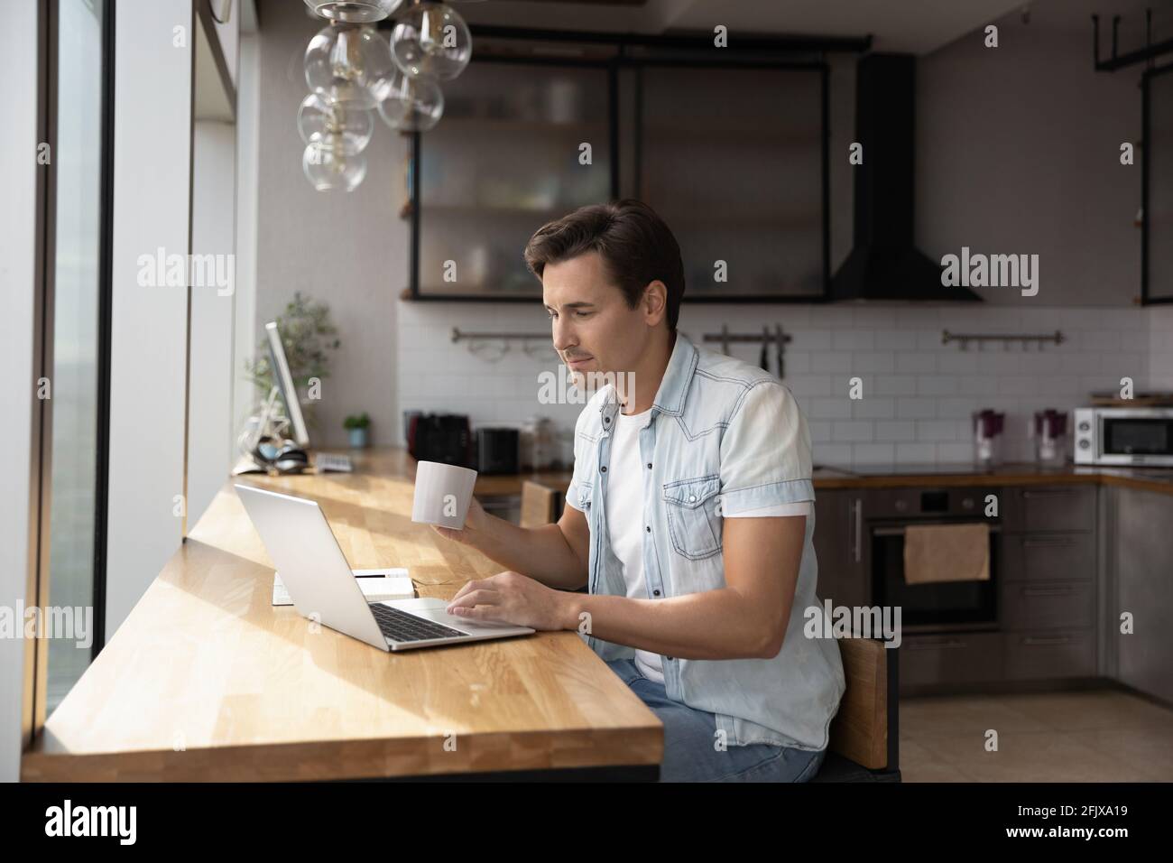 Caucasian man sit at home kitchen using laptop Stock Photo