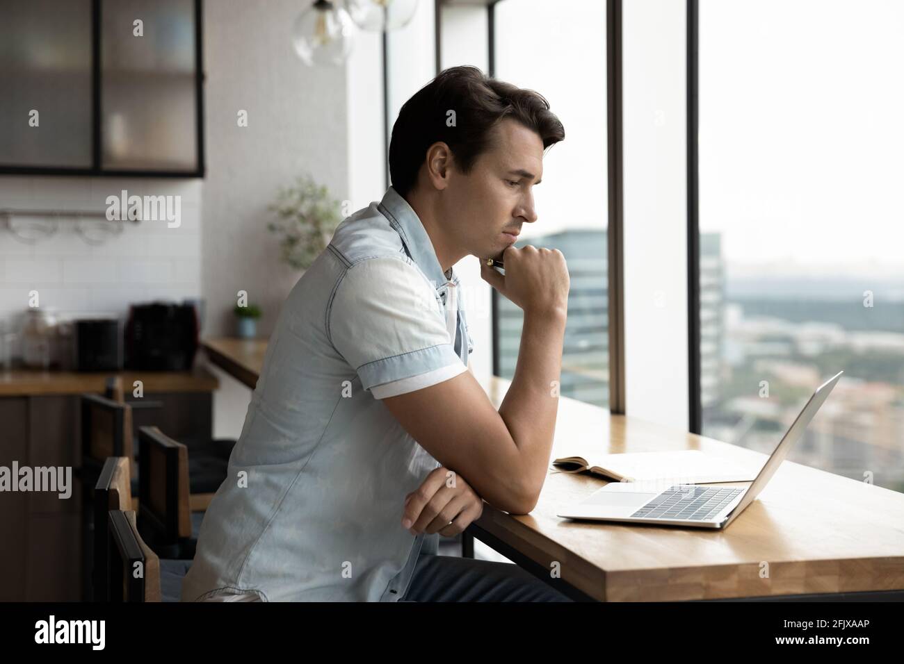 Pensive male employee work on laptop thinking Stock Photo