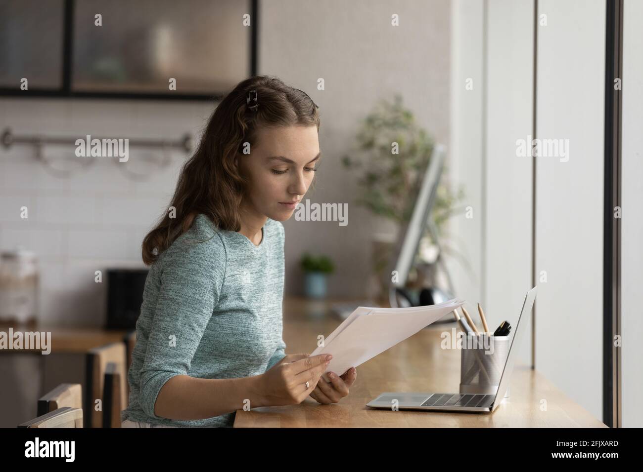 Young female employee work with documents using laptop Stock Photo