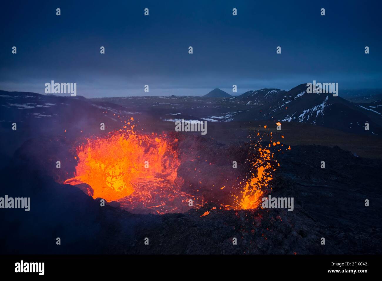 Volcanic terrain with burning hot lava in evening Stock Photo