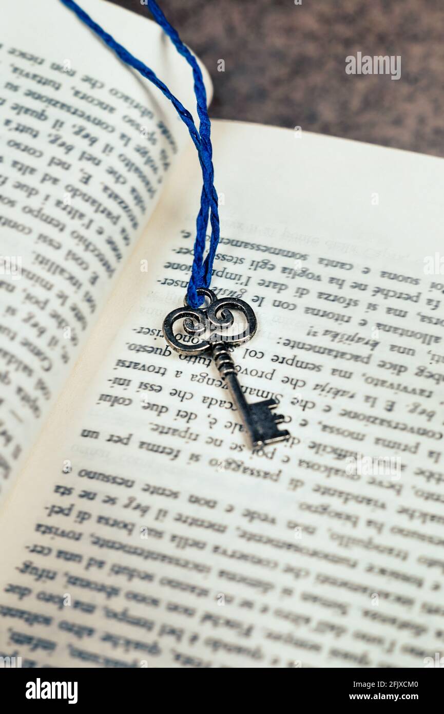 Silver key with blue string attached, placed on an open book Stock ...