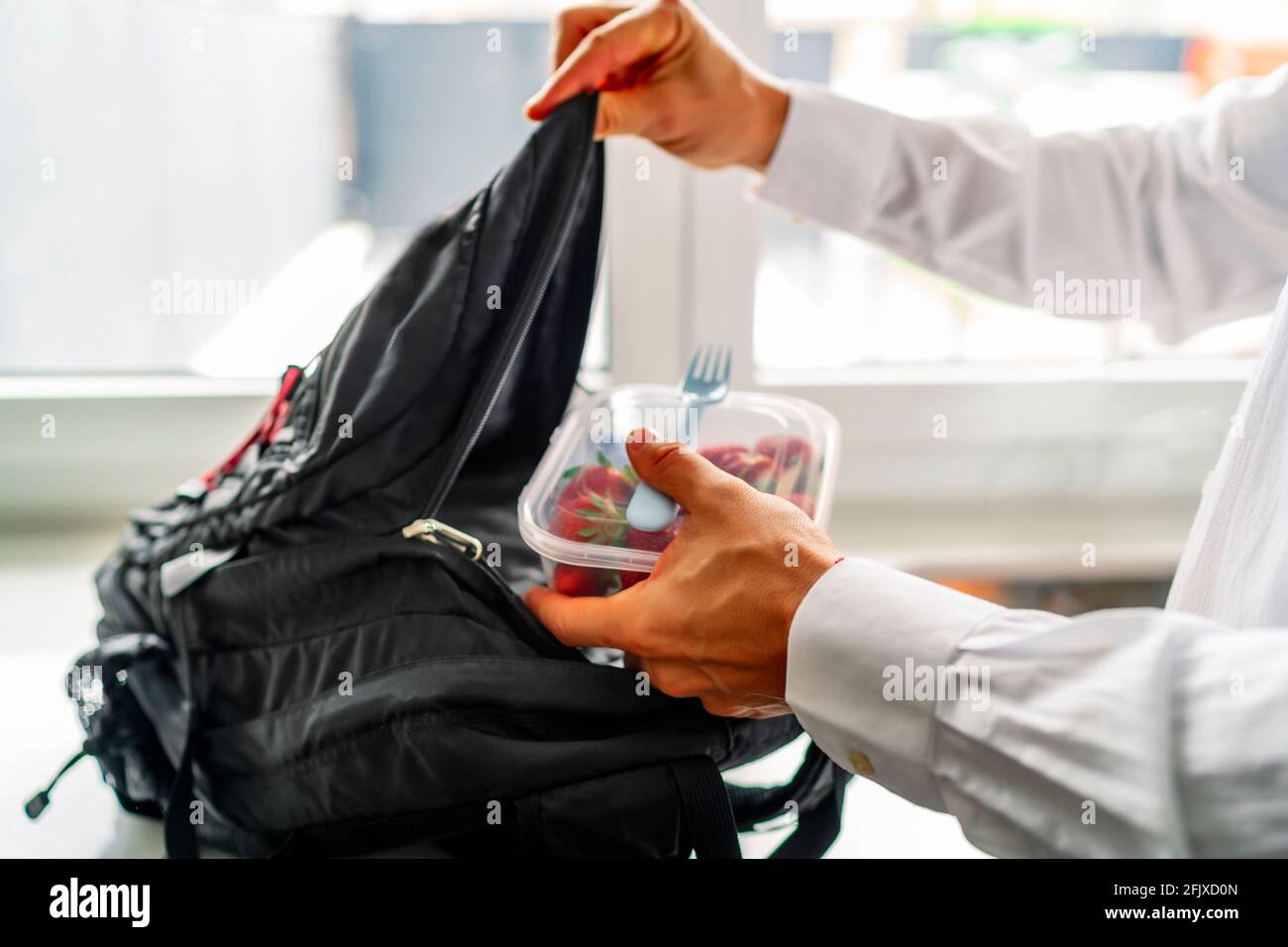 young man storing his healthy food tupperware in his backpack Stock