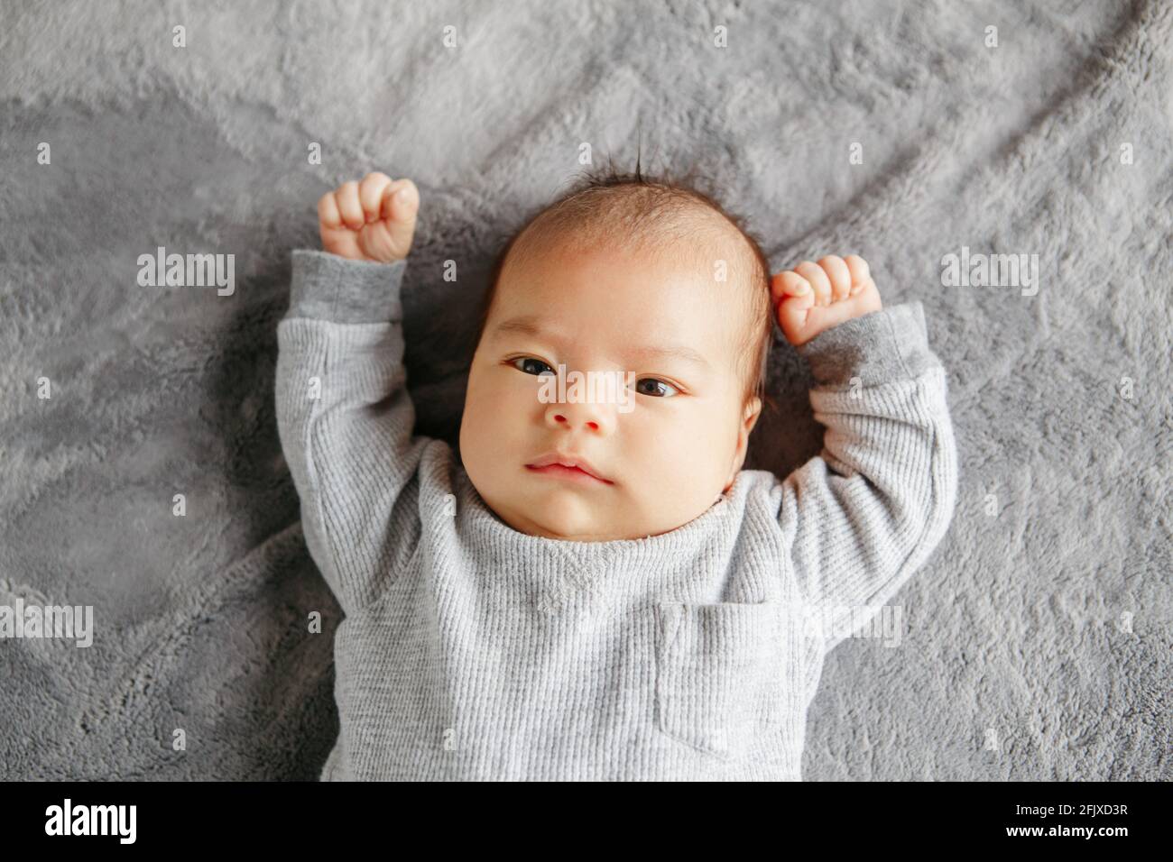 Cute two months newborn Asian Chinese baby boy lying on bed looking. Stock Photo