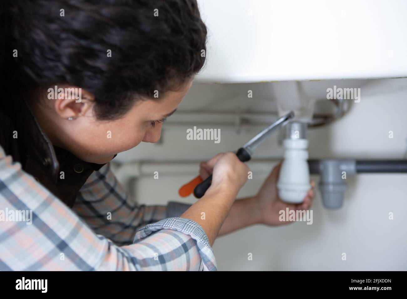 female plumber working on central heating boiler Stock Photo