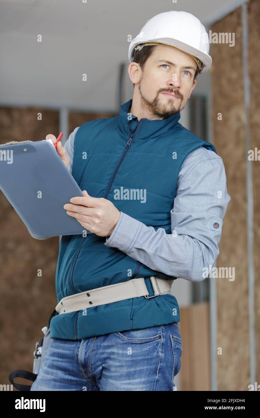male builder in helmet with clipboard taking notes Stock Photo