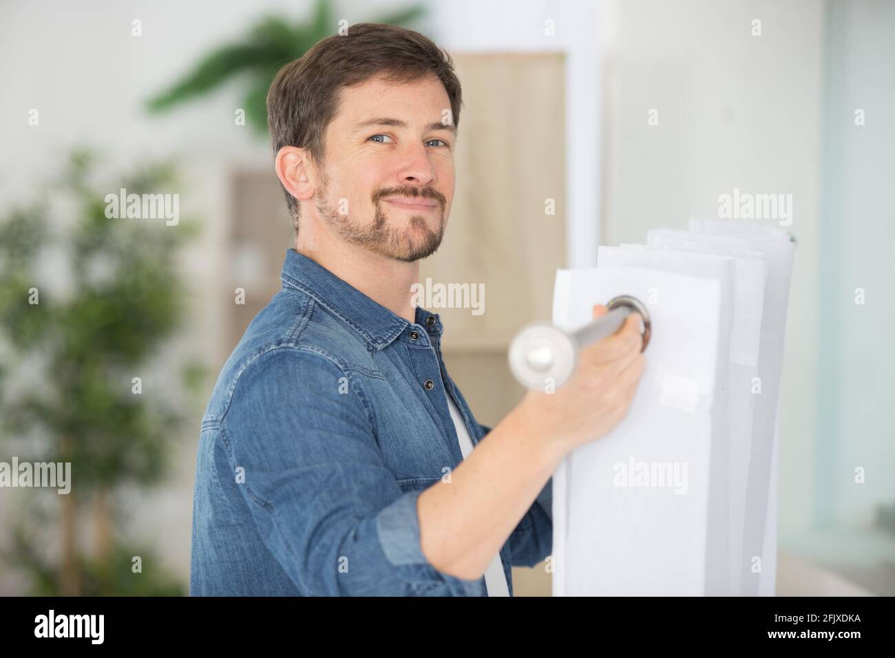 man fixing curtain on to rail Stock Photo