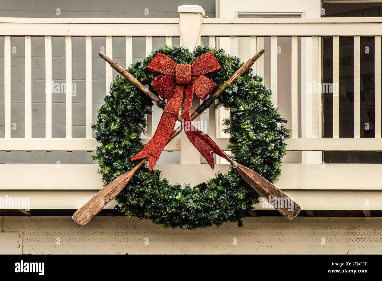 Nautical wreath with old worn oars and sparkly red bow mounted on wooden porch - closeup Stock Photo