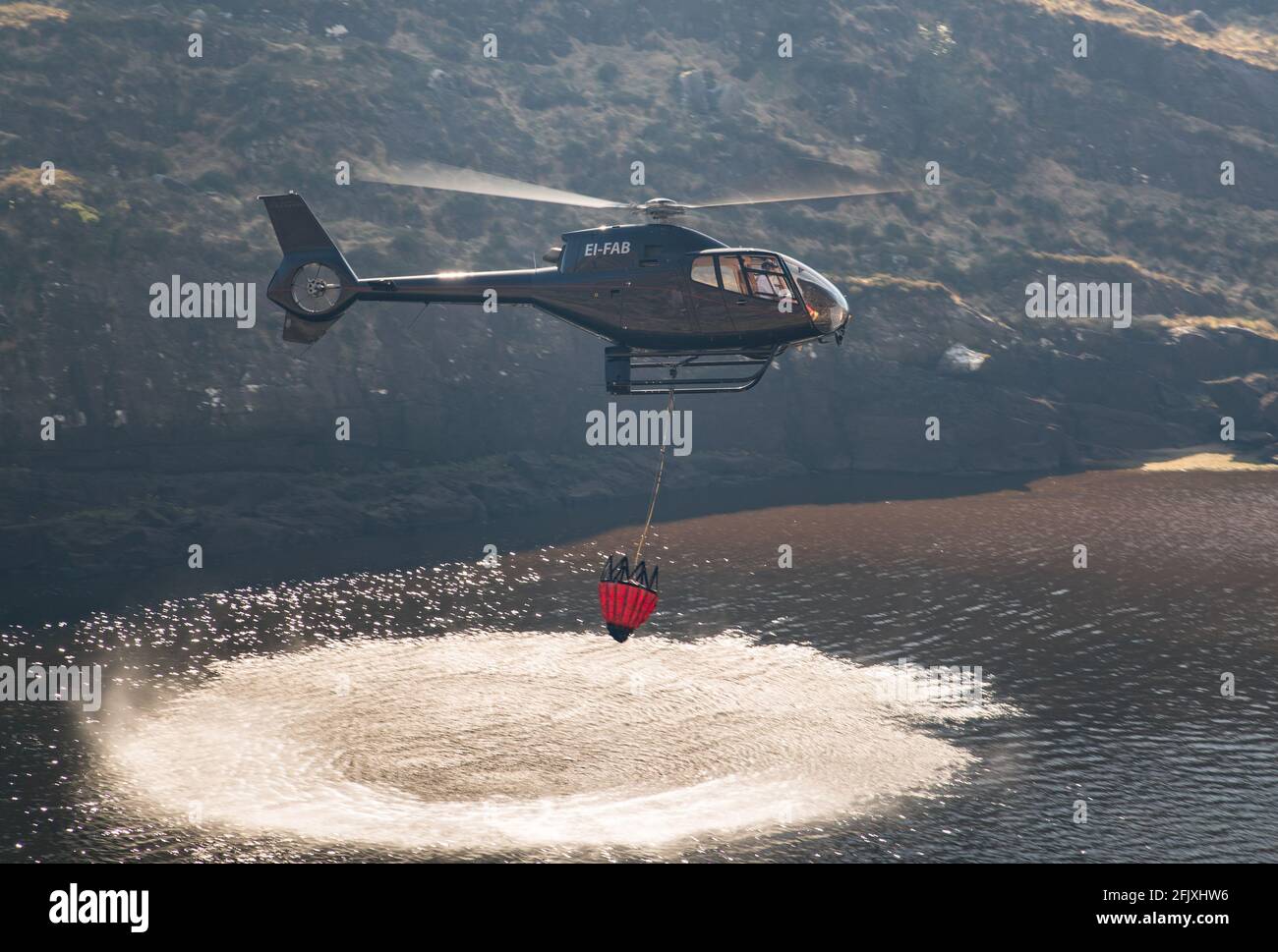 Killarney National Park, Ireland - 26th April.  2021:  Helicopter collecting water to extinguish fire in Killarney National park Stock Photo