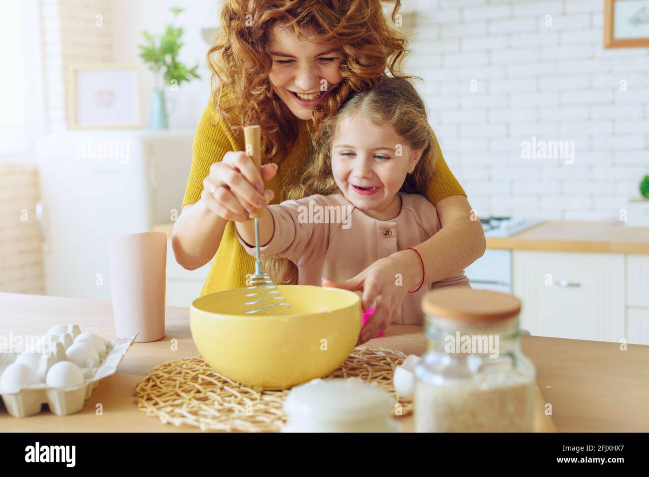 Mother and daughter prepare a cake together in the kitchen Stock Photo