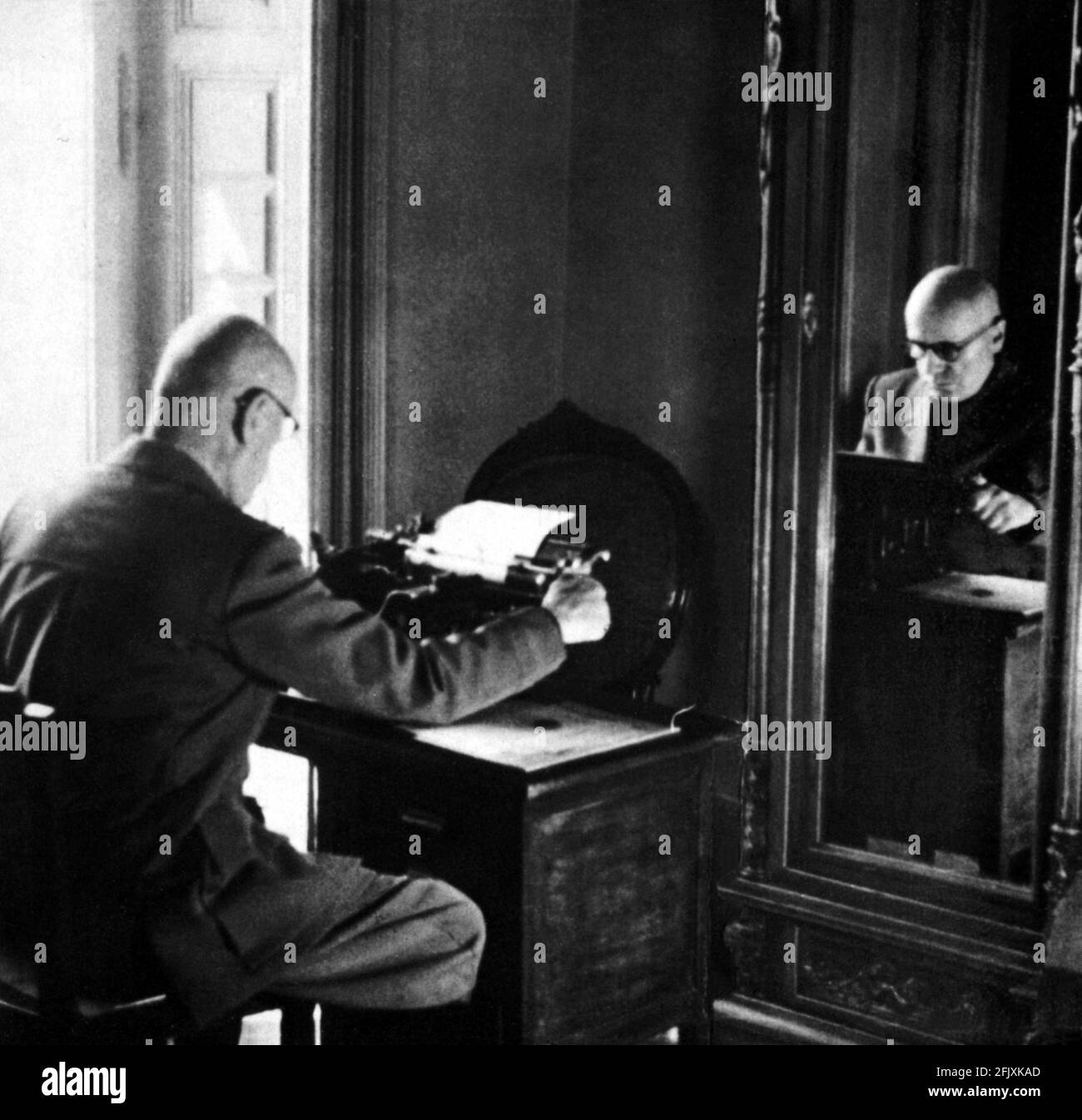 1943 -1944 , winter  , Gargnano , Lago di Garda , ITALY : The italian  Duce fascist  dictator BENITO MUSSOLINI at typewriter in his studio at Villa Feltrinelli  - World War 2nd - WW II - WWII - SECONDA GUERRA MONDIALE - FASCISTA - FASCIST - FASCISMO - FASCISM - occhiali - glasses - specchio - mirror  - scrivania - desk - macchina da scrivere - dittatore  ----  Archivio GBB Stock Photo