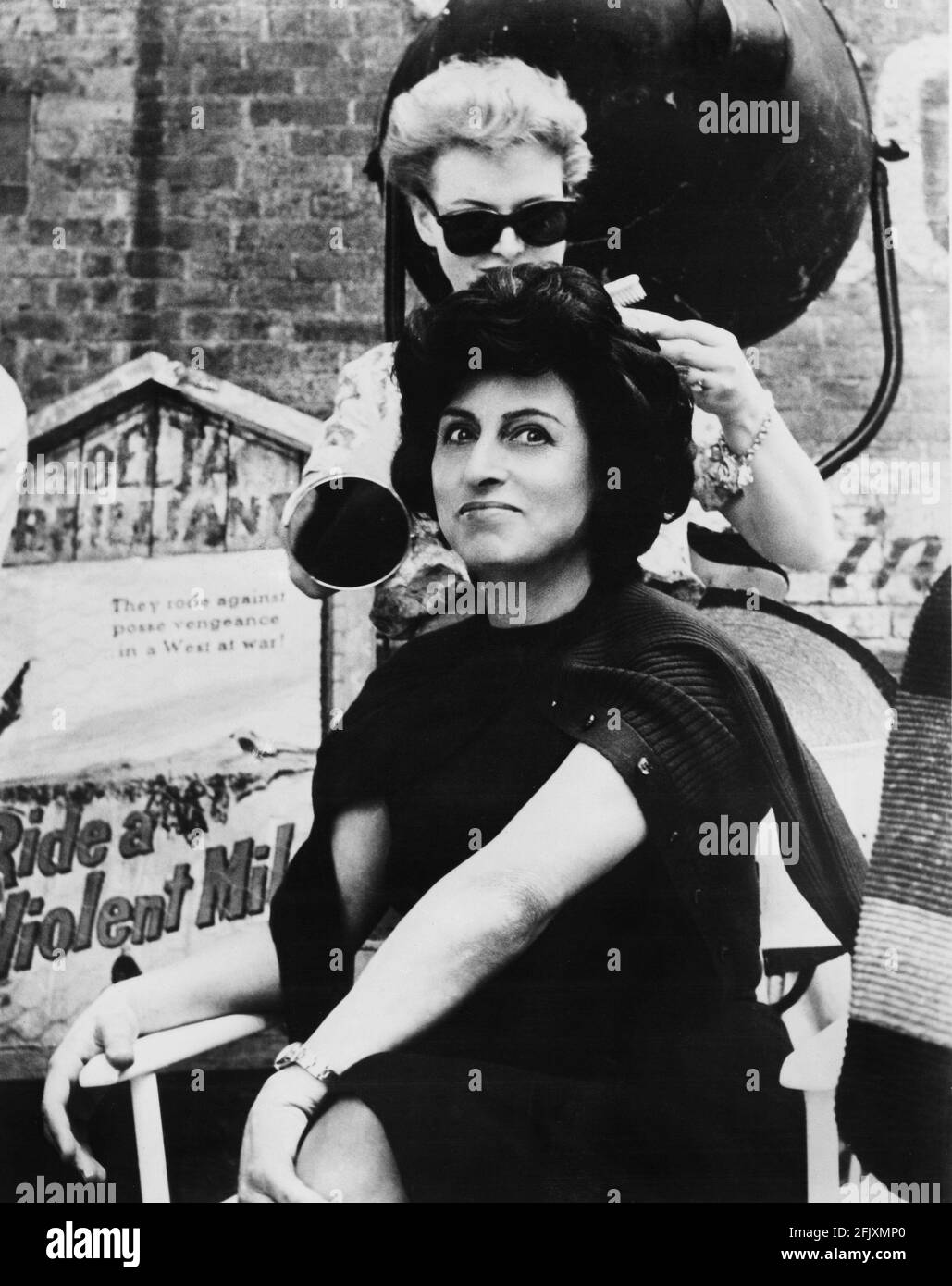 1959 : The italian movie actress ANNA  MAGNANI smiled for the camera on the set of  THE FUGITIVE KIND ( Pelle di serpente )  by Sidney Lumet , from a play by Tennessee Williams , United Artist Productions . Photo taken by actor Paul Newman . While her co-star JOANNE WOODWARD aid like hairdo repair the Magnani  after one of her tempestuos scenes. PAUL NEWMAN , husband of star JOANNE WOODWARD , visited the set and acted as part-time still photographer for the production.- CINEMA - FILM - attrice  - attore - parrucchiera - smile - sorriso - sul set  ----   Archivio GBB Stock Photo