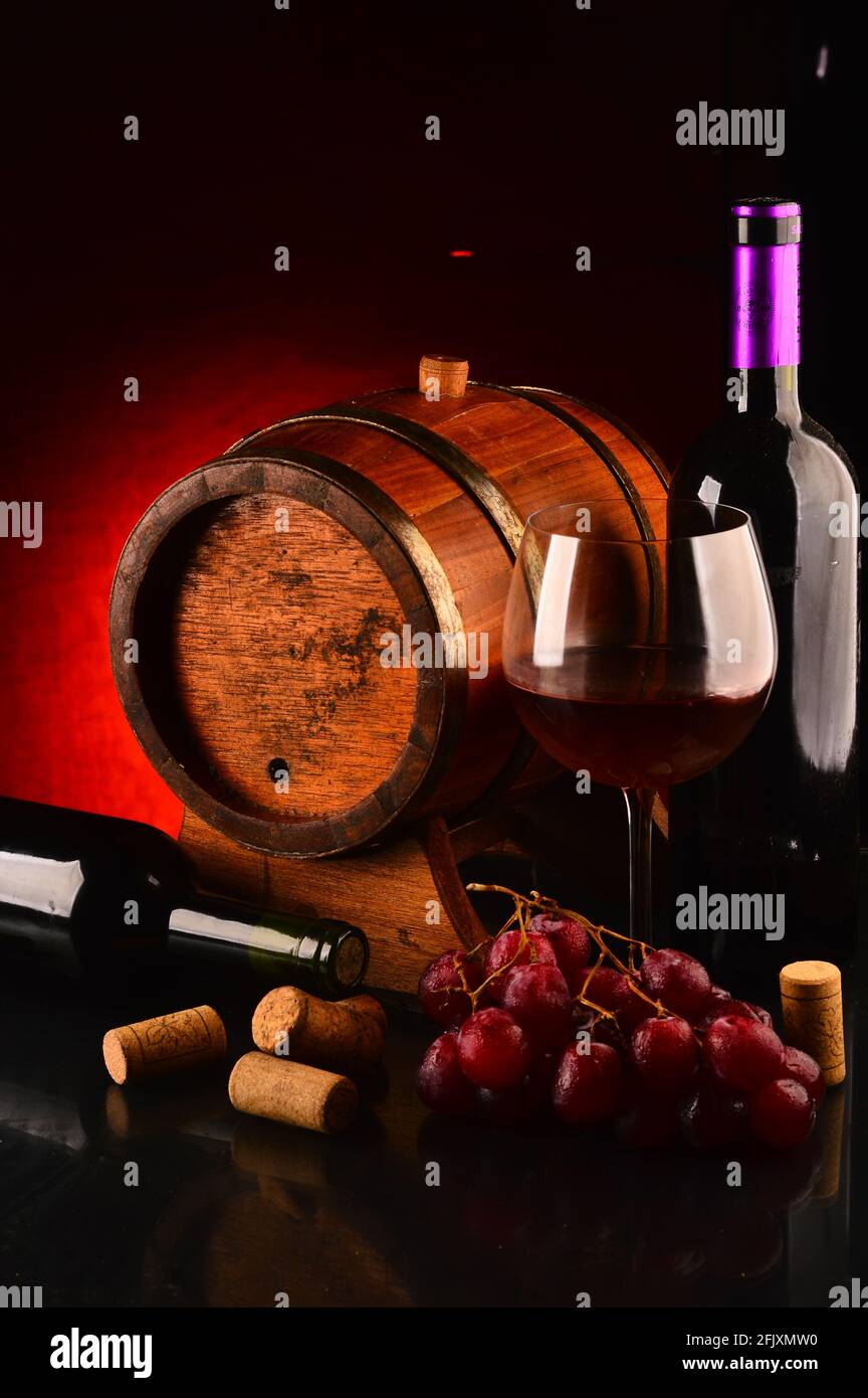 Glass and bottle of wine, wooden barrel and grapes on the table Stock ...