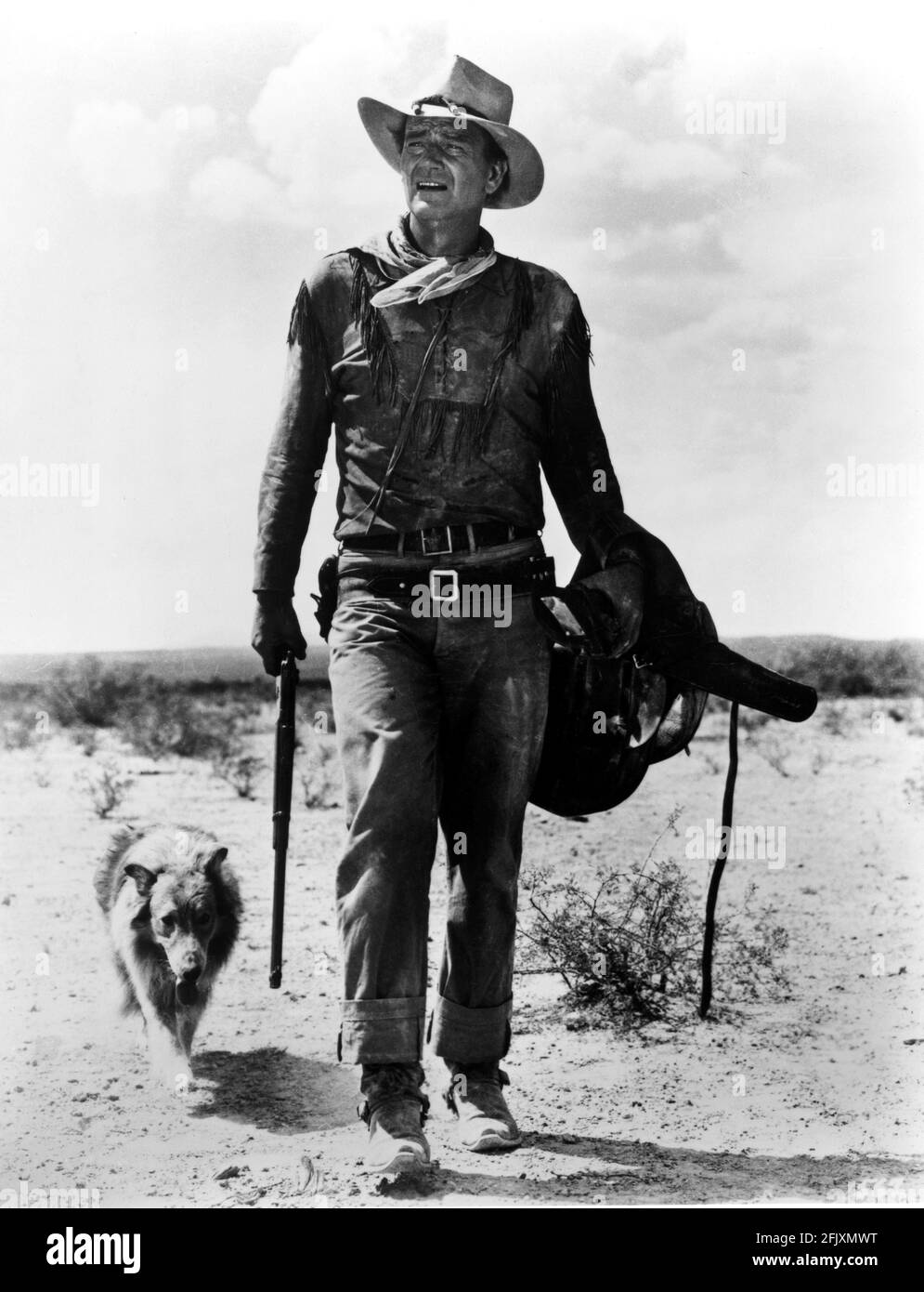 1960 , USA : The movie actor JOHN  WAYNE  ( 1907 - 1979 ) as DAVID CROCKETT  in THE ALAMO ( La battaglia di Alamo ) , directed by JOHN WAYNE himself  -  FILM - CINEMA - attore cinematografico -  cappello - hat - portrait - ritratto - WESTERN - WILDE WEST - dog - cane - fucile - rifle - gun - belt - cintura - sella - JEANS - desert - deserto - stivali - boots  -  foulard - bandanna  ----   Archivio GBB Stock Photo