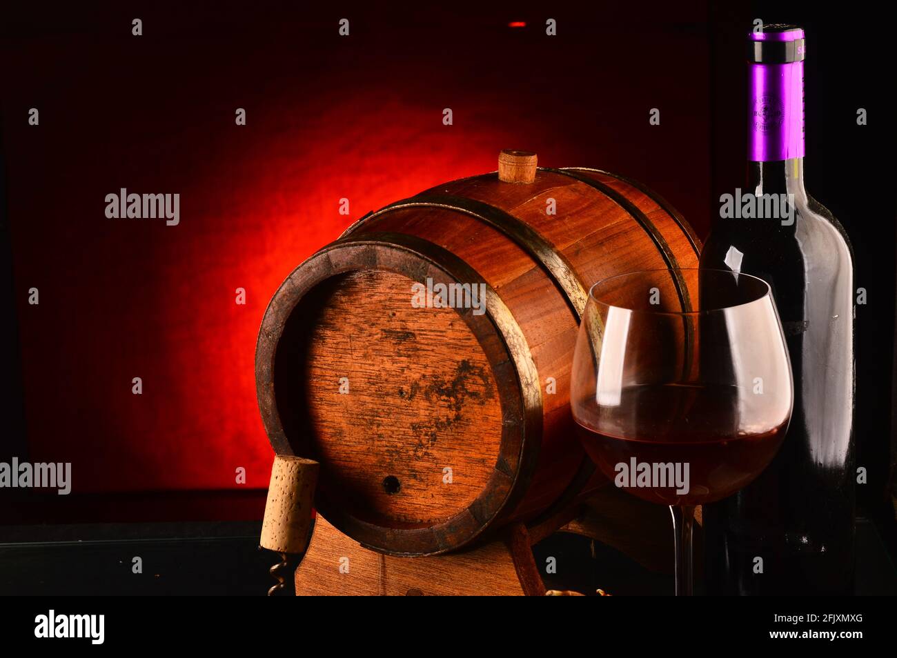 Glass and bottle of wine, wooden barrel and grapes on the table Stock ...