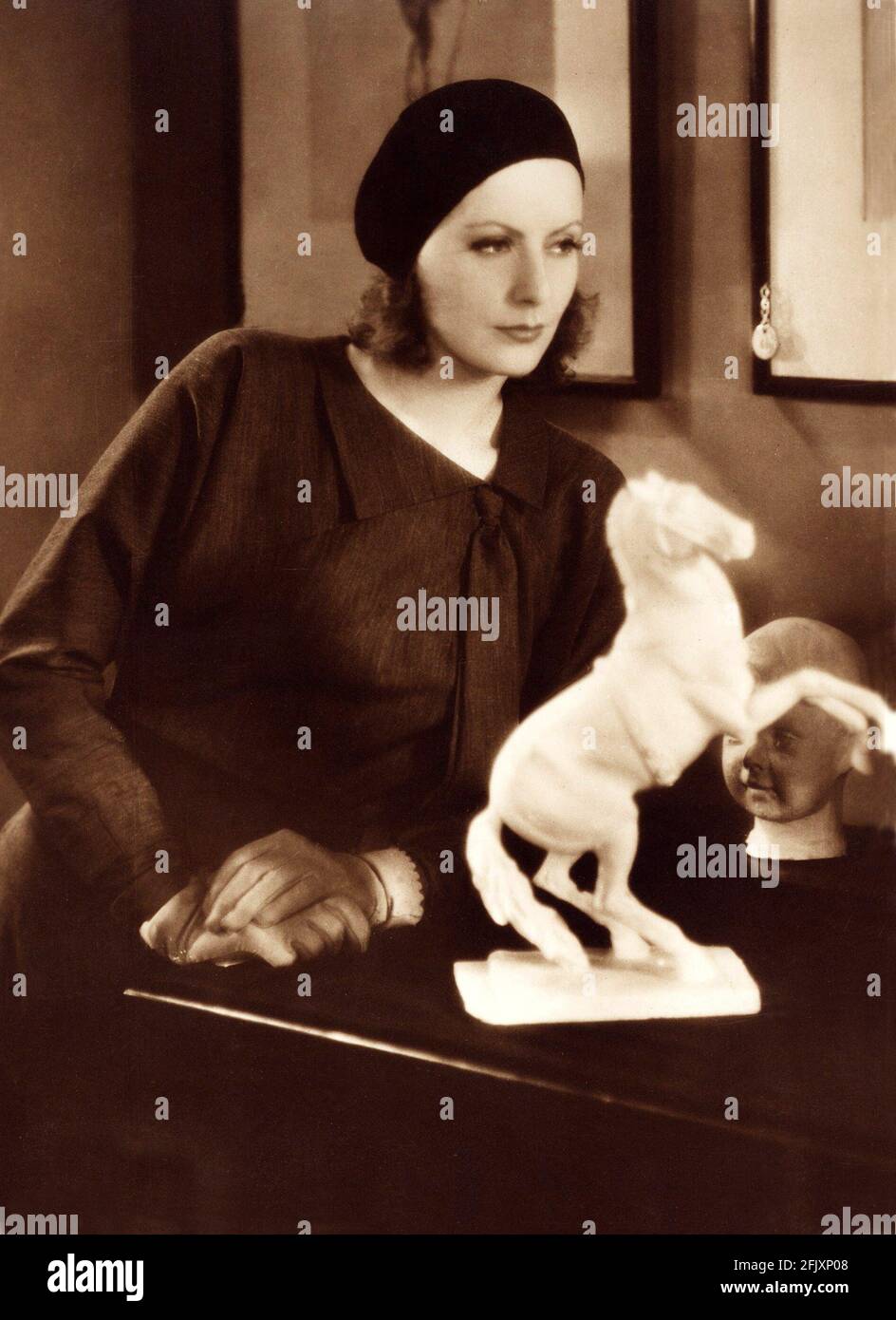 1929  , USA : The actress GRETA GARBO   in  THE KISS ( Il bacio )  by  Jacques Feyder , from a novel by George M. Saville  - MGM - SILENT MOVIE - FILM - CINEMA MUTO - portrait - ritratto - hat - cappello - basco -  cavallo statue - sculpture - scultura equestre - cavallo - forniture - arredamento - guanti - guanto - gloves - colletto - collar  ----  Archivio GBB Stock Photo