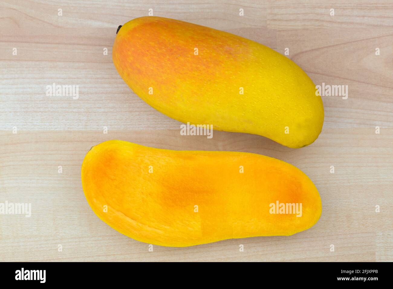 Maha chanok Rainbow mango cut in half showing yellow orange texture, hybrid fruit between Sunset