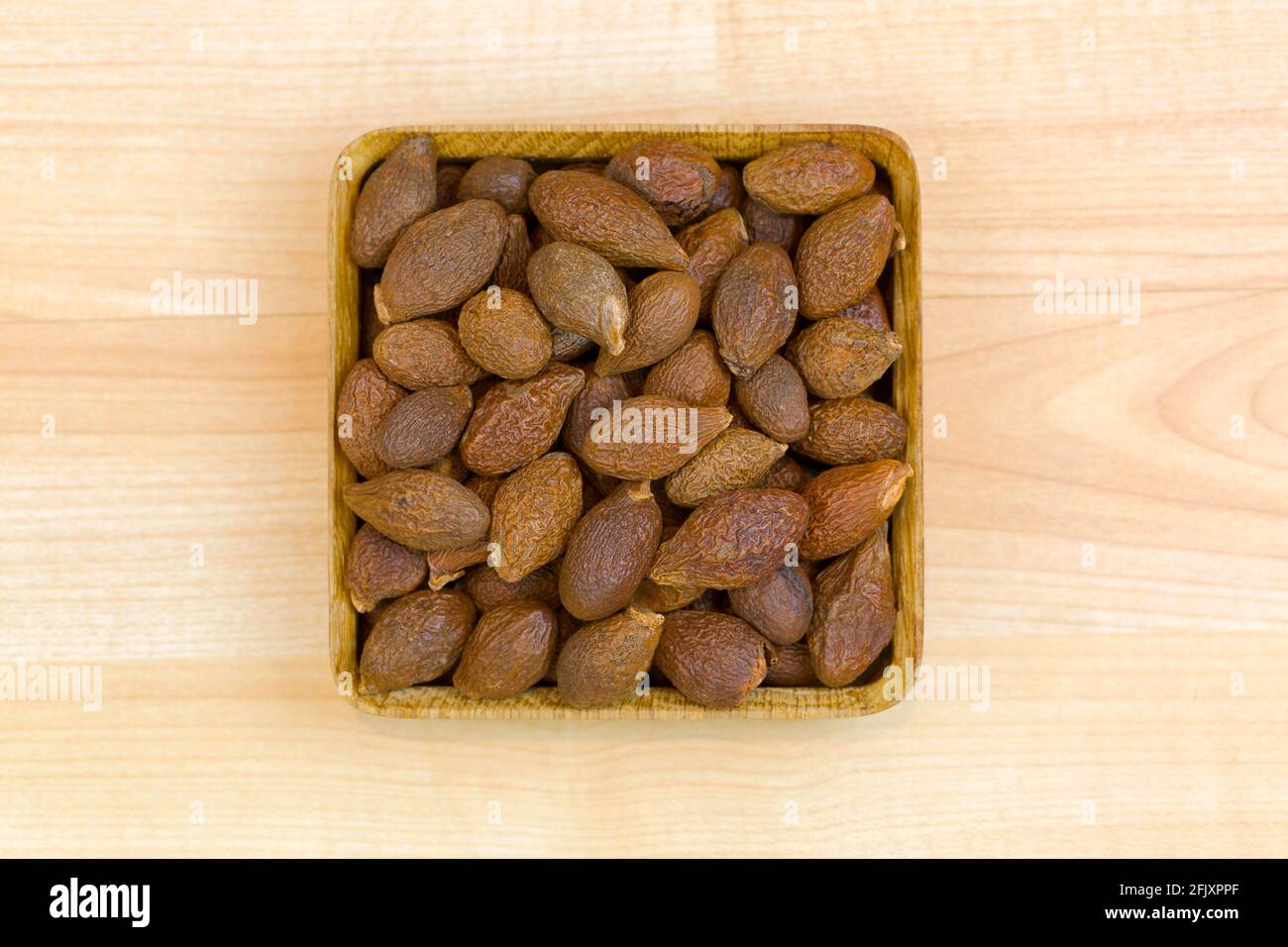 Dried seeds of Malva nut (Taiwan sweet gum) used in traditional Chinese medicine, top view on wooden background (Scaphium affine) Stock Photo