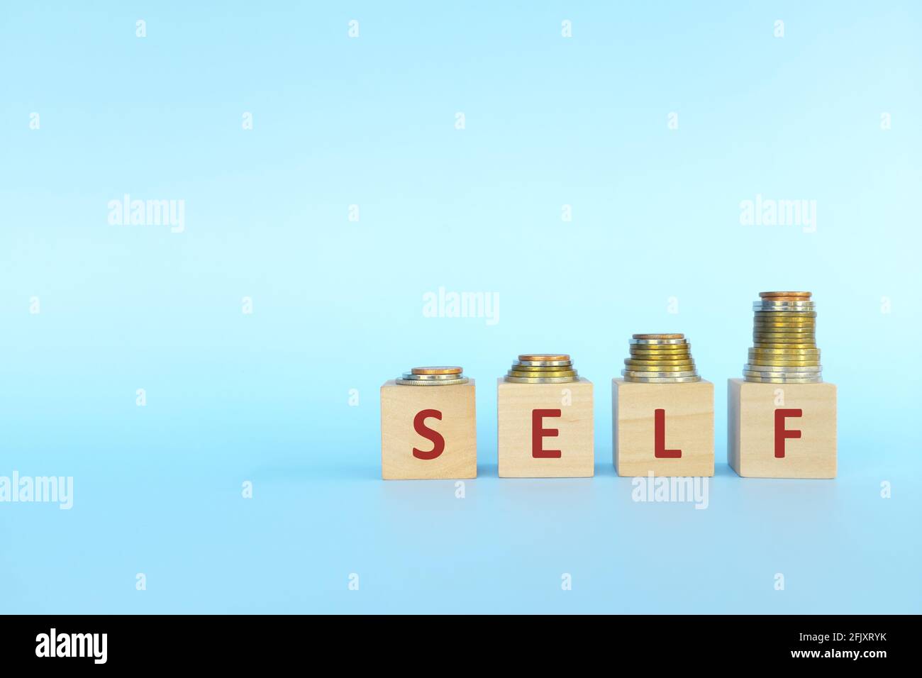 Increasing stack of coins with word self on wooden blocks in blue background. Invest on yourself improvement concept. Stock Photo