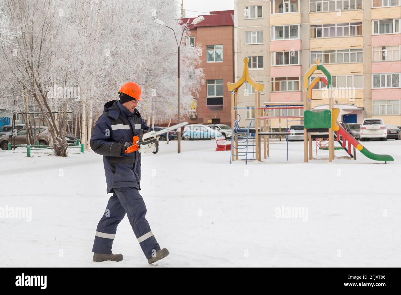 Worker with a chainsaw in hand at the assembly site Stock Photo