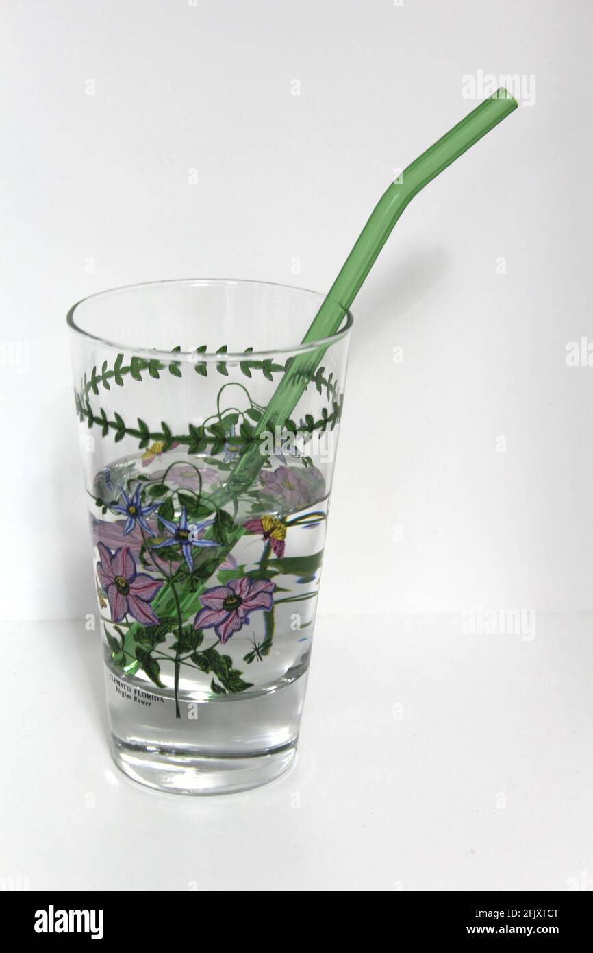 Colorful reusable glass straw in a clear glass cup. An alternative replacement for classic disposable plastic drinking straw great for the environment Stock Photo